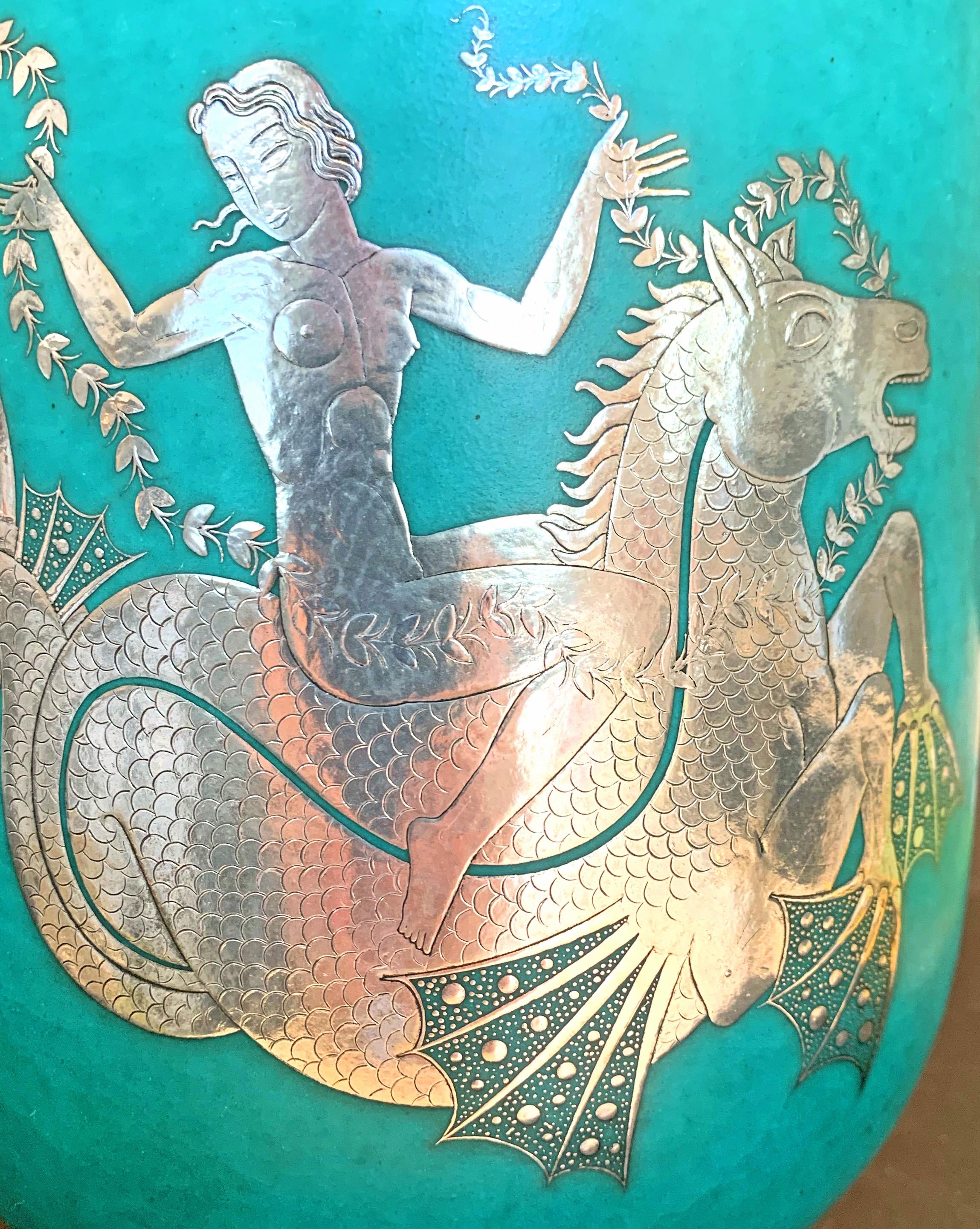 Étonnante par sa taille, sa composition et son exécution, cette grande jarre couverte de la manufacture de porcelaine de Gustavsberg en Suède présente une figure de sirène très détaillée chevauchant une créature mythologique, l'hippocampe, le tout