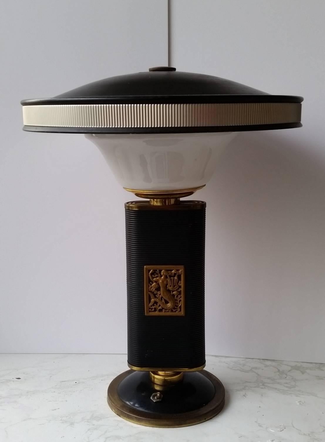 Magnificent Eileen gray table lamp - in metal, glass and celluloid decorated with a cartouche featuring a siren playing the lyre.
Model created for the house Jumo in the years 1930-1940
Measures: Height 48 cm and diameter 39 cm
In good condition