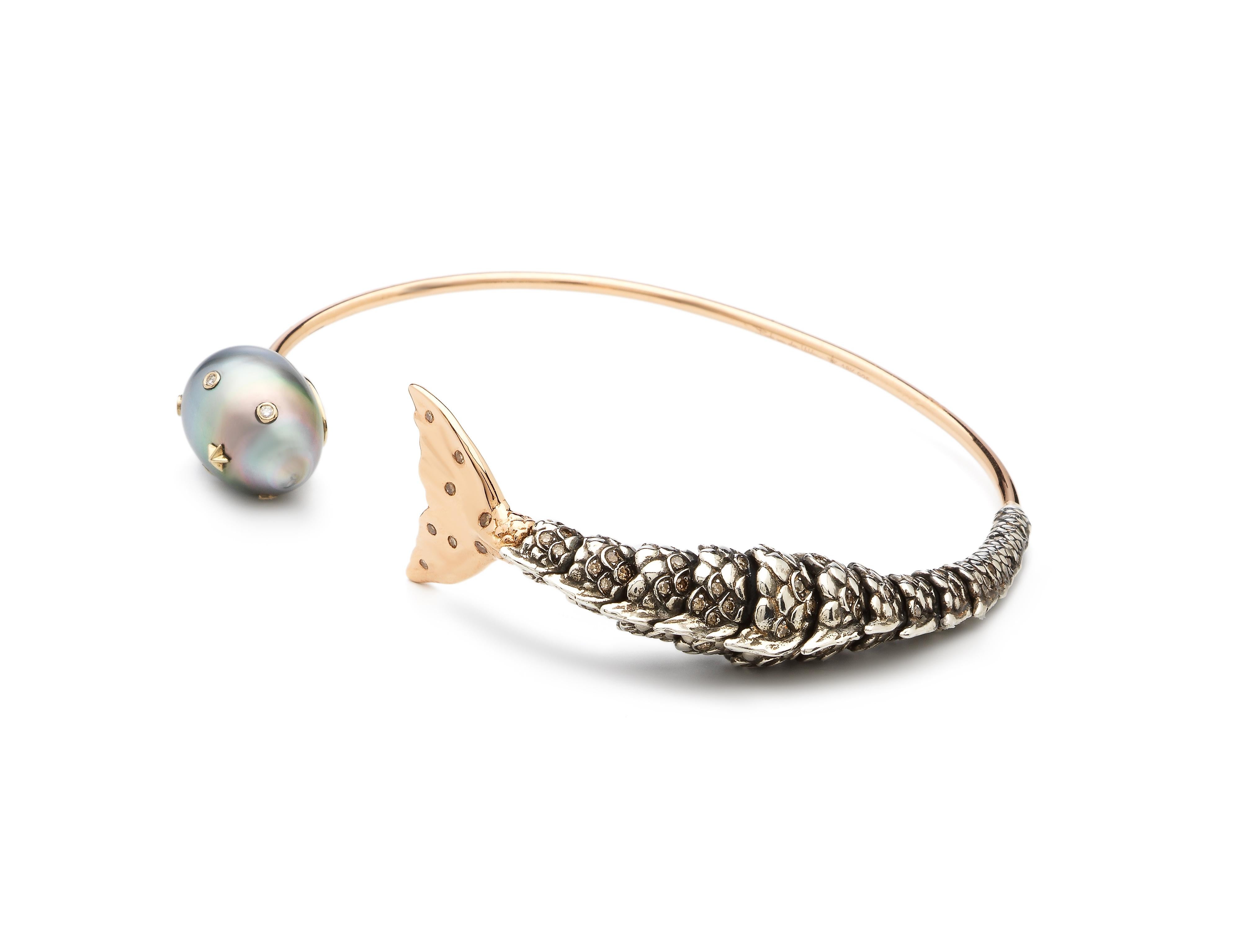 This delicate bangle is designed in 18k rose gold as an open-ended design. At one end sits a luminous Tahitian pearl, embellished with diamonds and gold stars, while at the opposite end is a mermaid’s tail, fashioned in rose gold and sterling