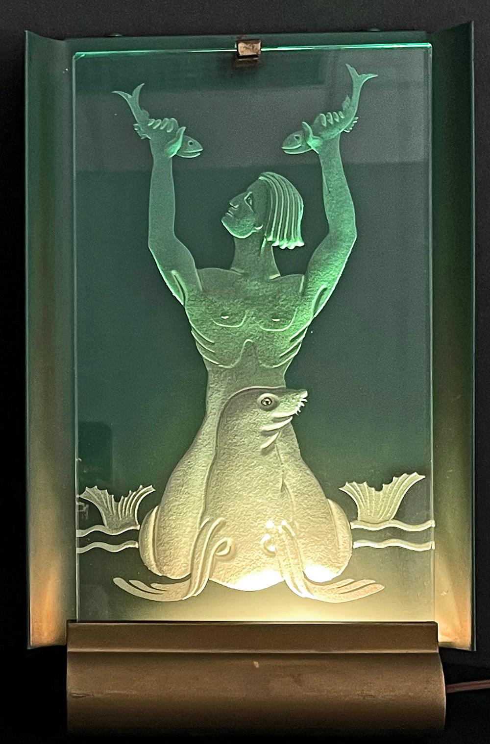 Rare and striking, this pair of Art Deco illuminated sconces depict two aquatic scenes: a merman riding a seal and holding two fish aloft; and a pair of fish twisting in the Art Deco currents. Crafted in Sweden, where underwater themes were common