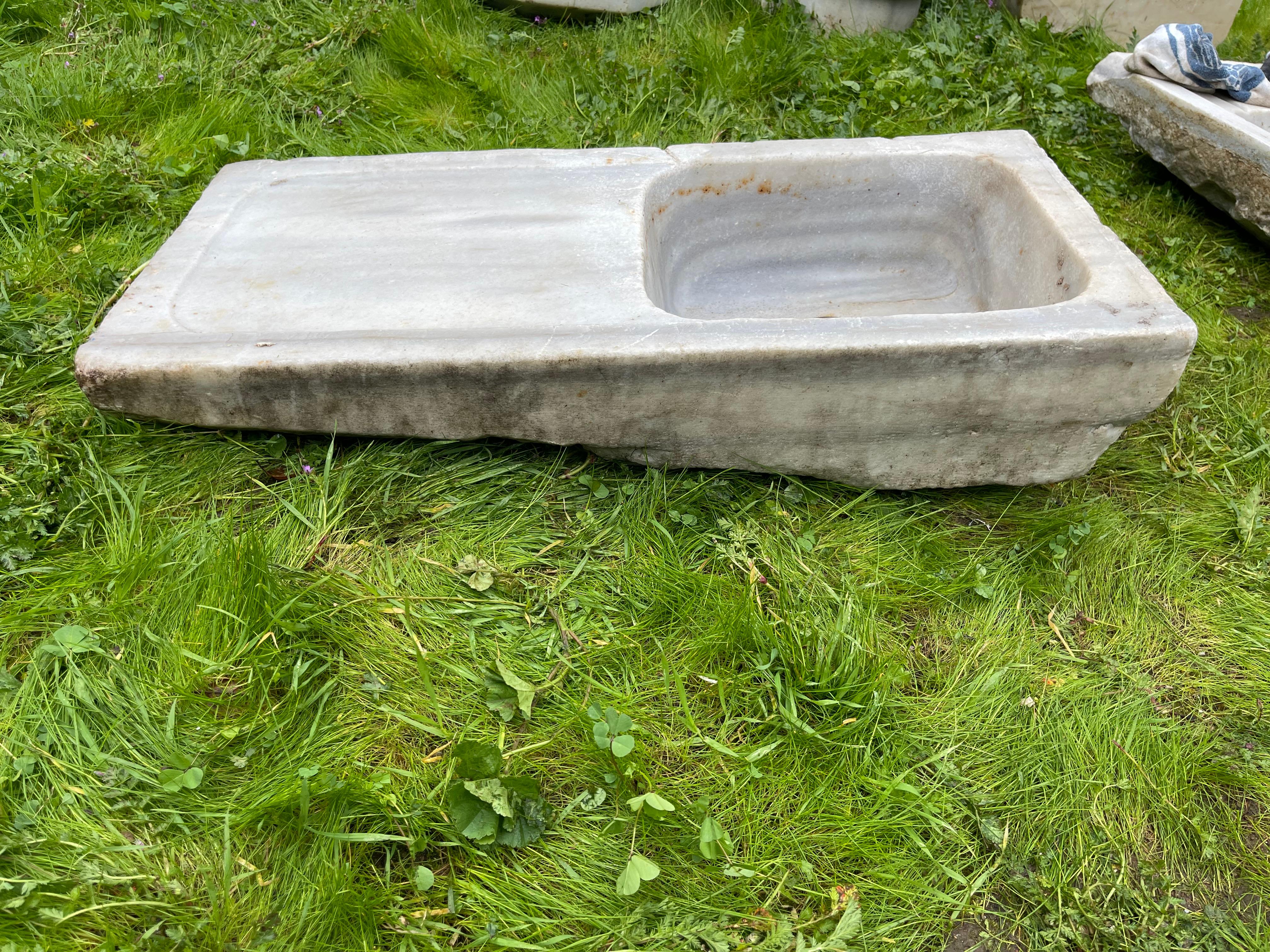 Questo lavandino vintage in marmo presenta dettagli intagliati a mano che ci trasportano nei bagni comuni dell'Impero Ottomano, chiamati hamam. Questo lavello è caratterizzato da una forma rettangolare e da ampi piani d'appoggio con eleganti