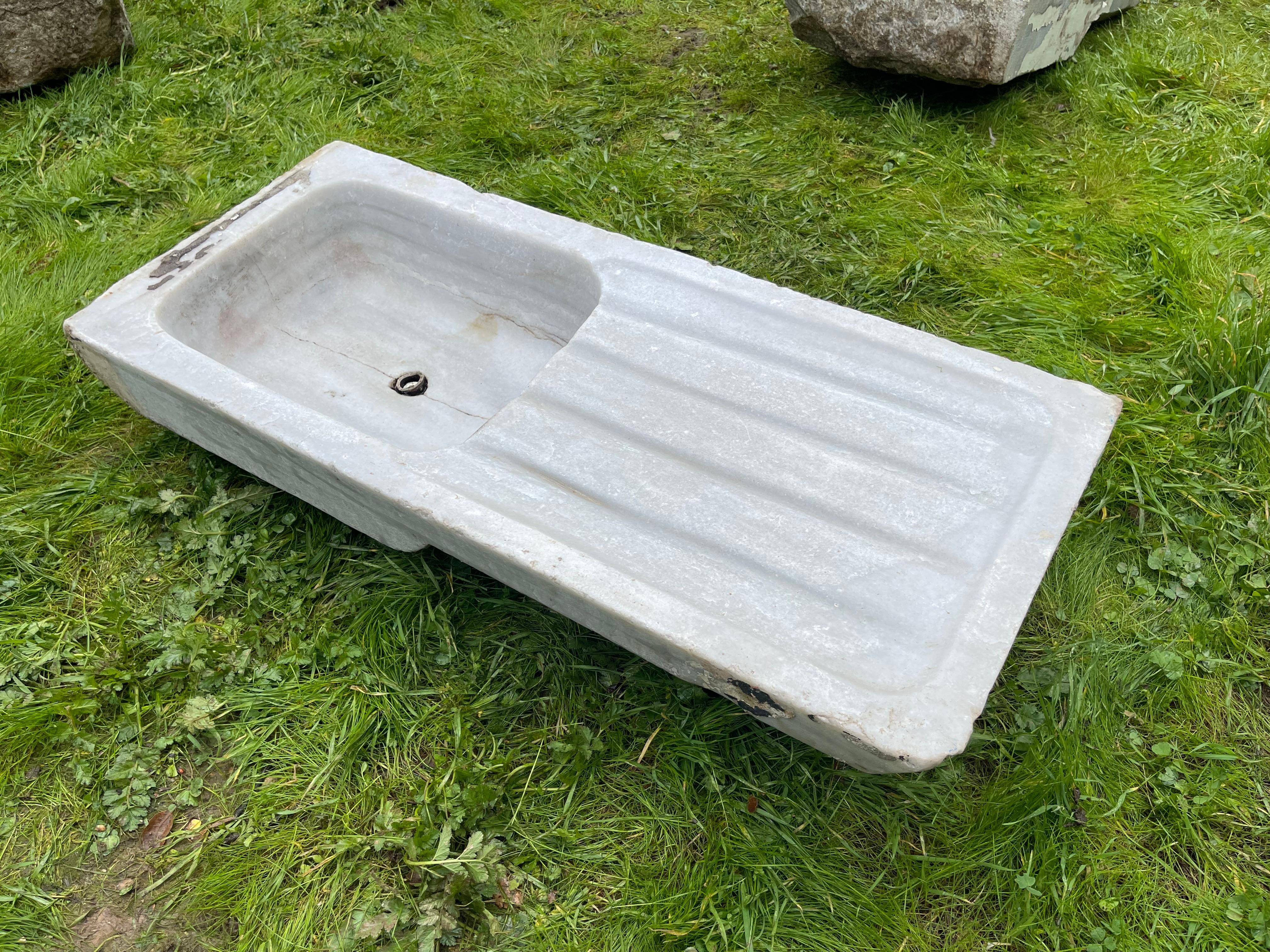 Ce lavabo en marbre vintage présente des détails sculptés à la main qui nous transportent dans les bains publics de l'Empire ottoman, appelés hamams. Cet évier se caractérise par une forme rectangulaire et de larges plans de travail dotés d'élégants