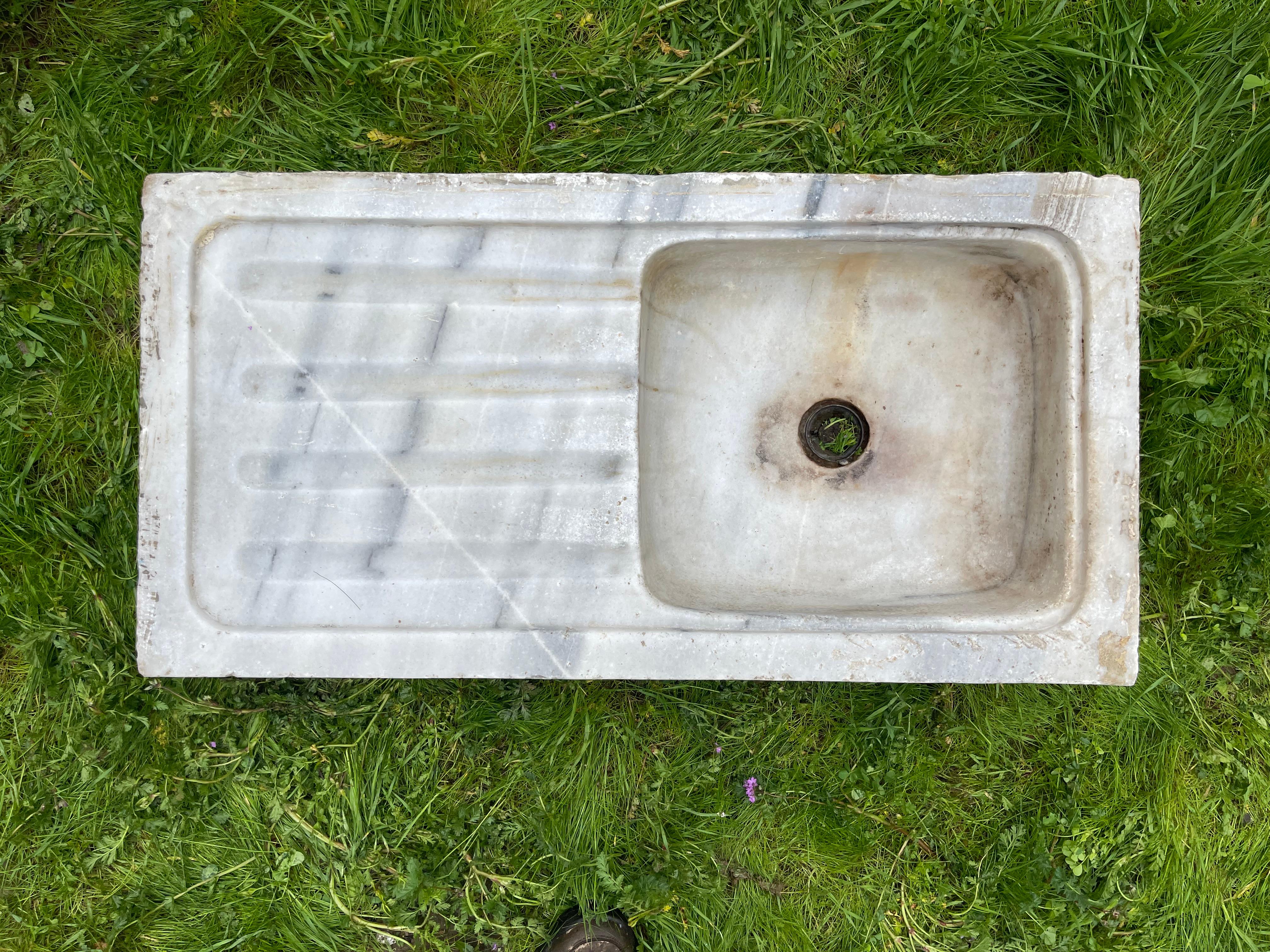 Ce lavabo en marbre vintage présente des détails sculptés à la main qui nous transportent dans les bains publics de l'Empire ottoman, appelés hamams. Cet évier se caractérise par une forme rectangulaire et de larges plans de travail dotés d'élégants