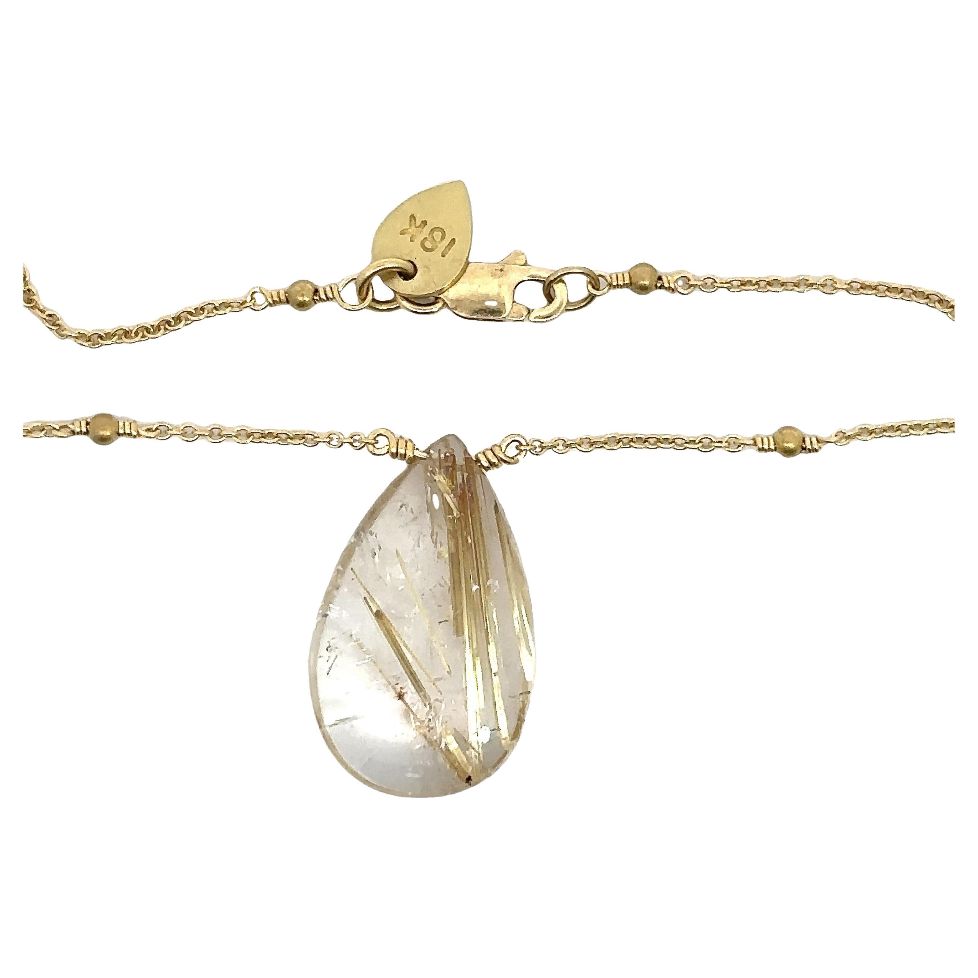 Questa splendida collana Me&Ro presenta un quarzo rutilato a forma di pera che misura circa 0,75 pollici per 0,50 pollici. Il quarzo è incastonato in una catena d'oro giallo 18KT da 18 pollici, delicatamente ornata da stazioni di perline d'oro. La