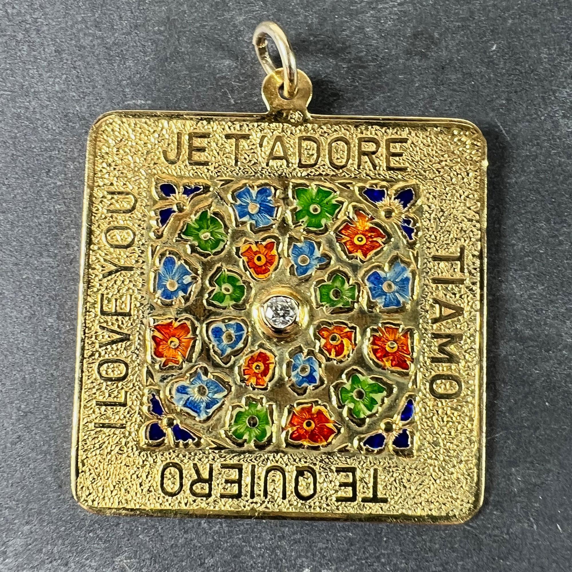 A square 18 karat (18K) yellow gold love charm pendant with a round brilliant cut diamond collet set to the centre of a field of flowers in red, blue and green enamel on a textured background. Surrounding it are phrases in English, French, Italian,
