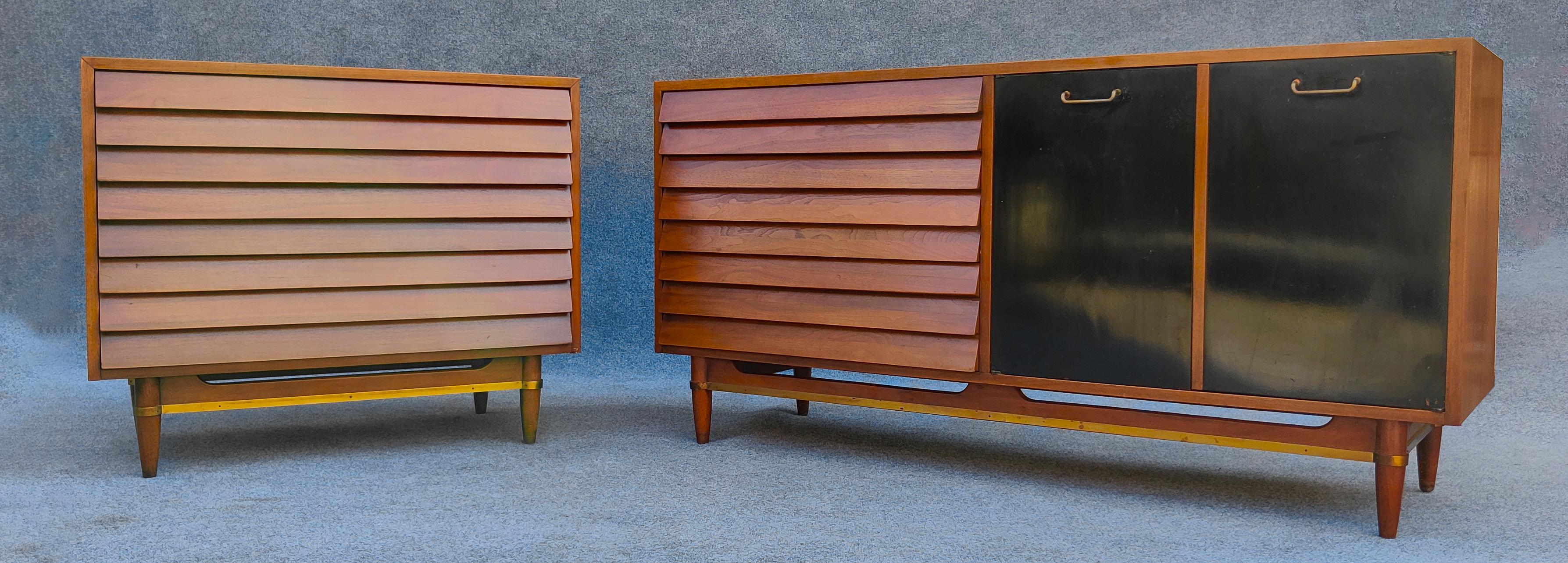 This stylish and cool set of Mid Century Modern dressers were designed by Merton Gershun for American of Martinsville. Featuring one large dresser and a small one, they each feature three large louvered drawers. The long dresser has two black doors