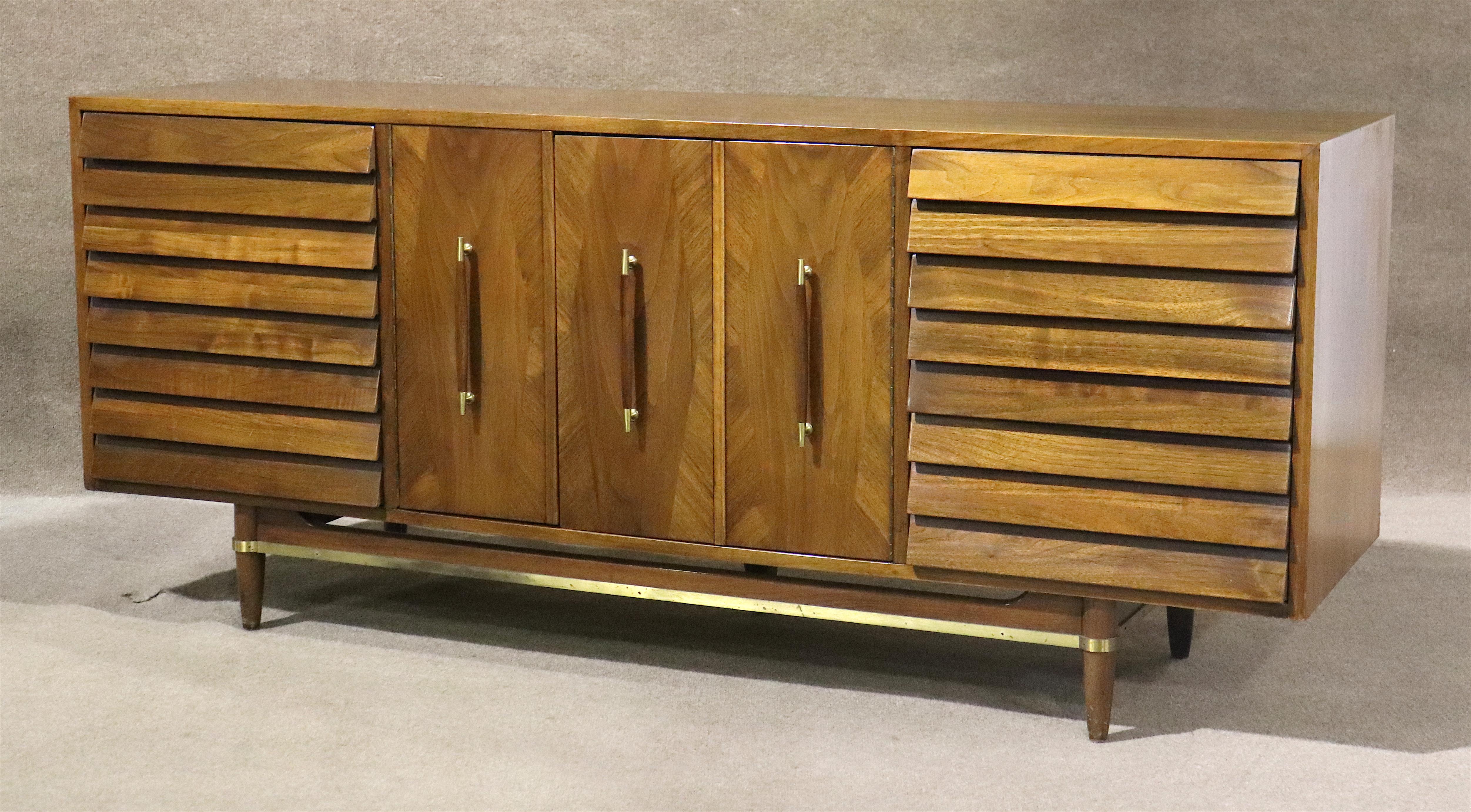 Merton Gershun designed dresser for his 'Dania' line with American of Martinsville. Beautiful walnut wood grain throughout with inlaid flourishes around the sculpted handles. Louvered front drawers and brass trimming accents the vintage modern