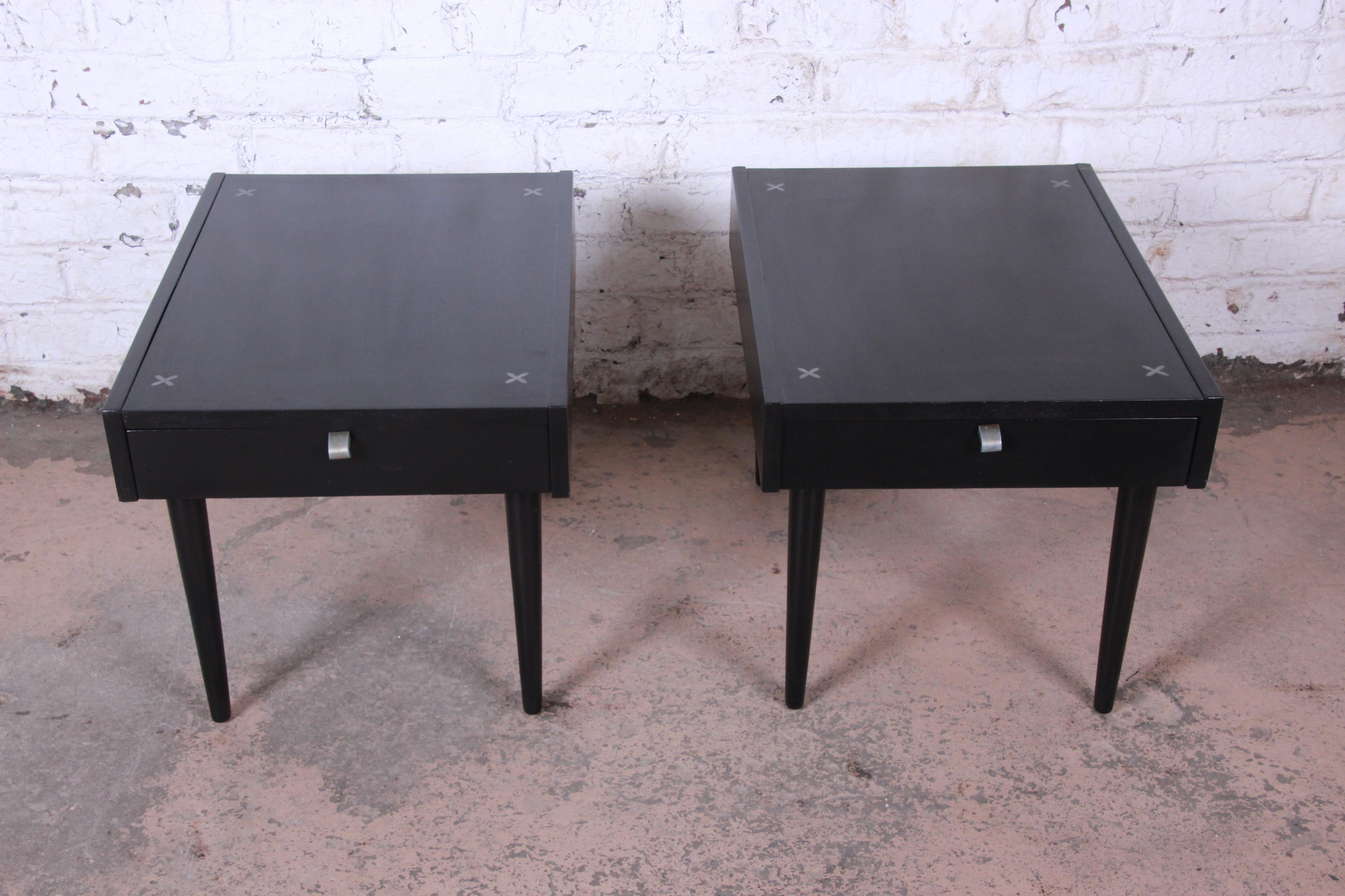 Offering an exceptional pair of mid-century modern nightstands or end tables designed by Merton Gershun for American of Martinsville. The tables feature a stunning newly ebonized finish and the iconic aluminium X-shaped inlays on top. The tables