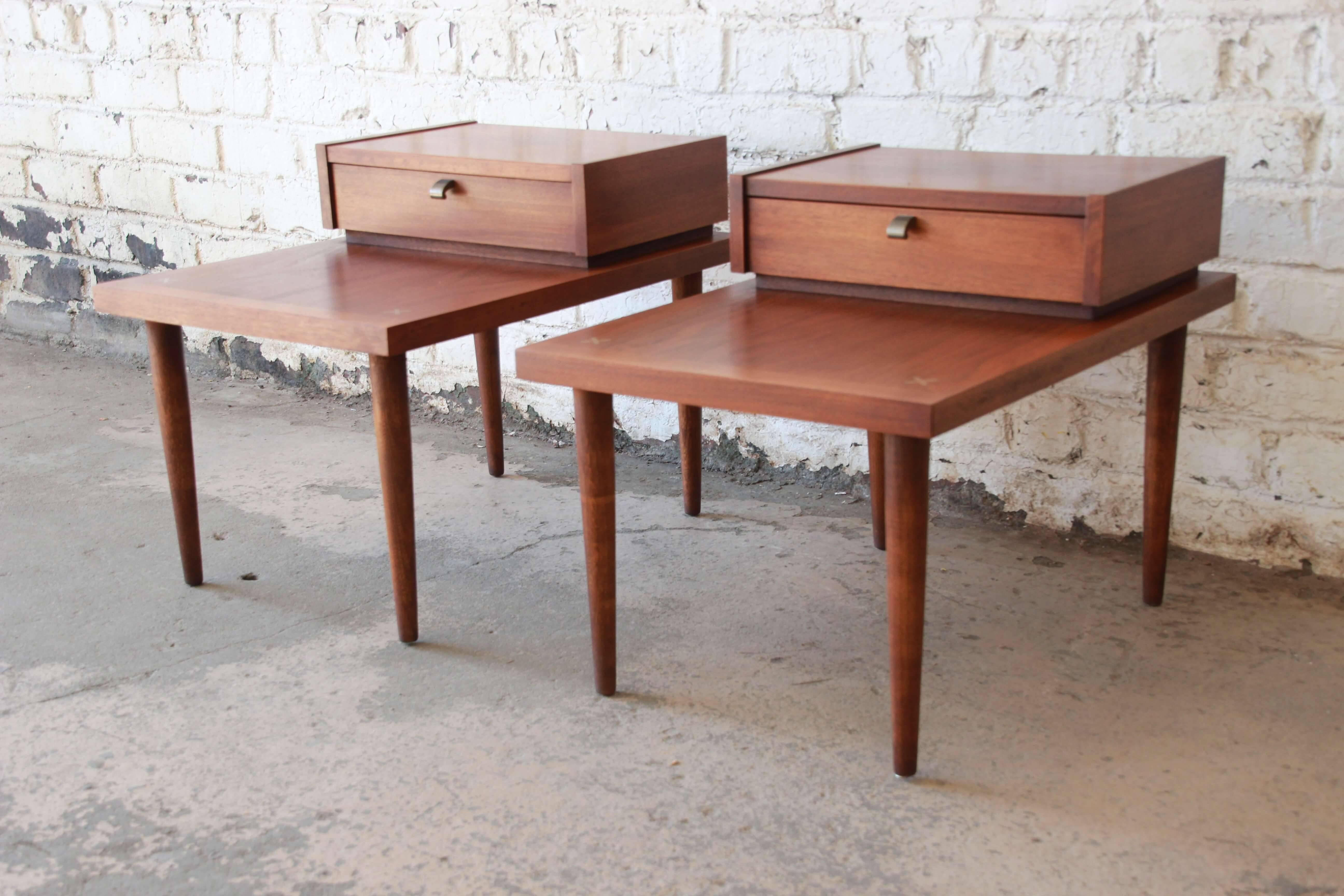 Offering a very nice pair of Mid-Century Modern end table or nightstands by Merton Gershun for American of Martinsville. The tables are in original condition with brass inlaid details and unique pulls. The step end design has a low profile version