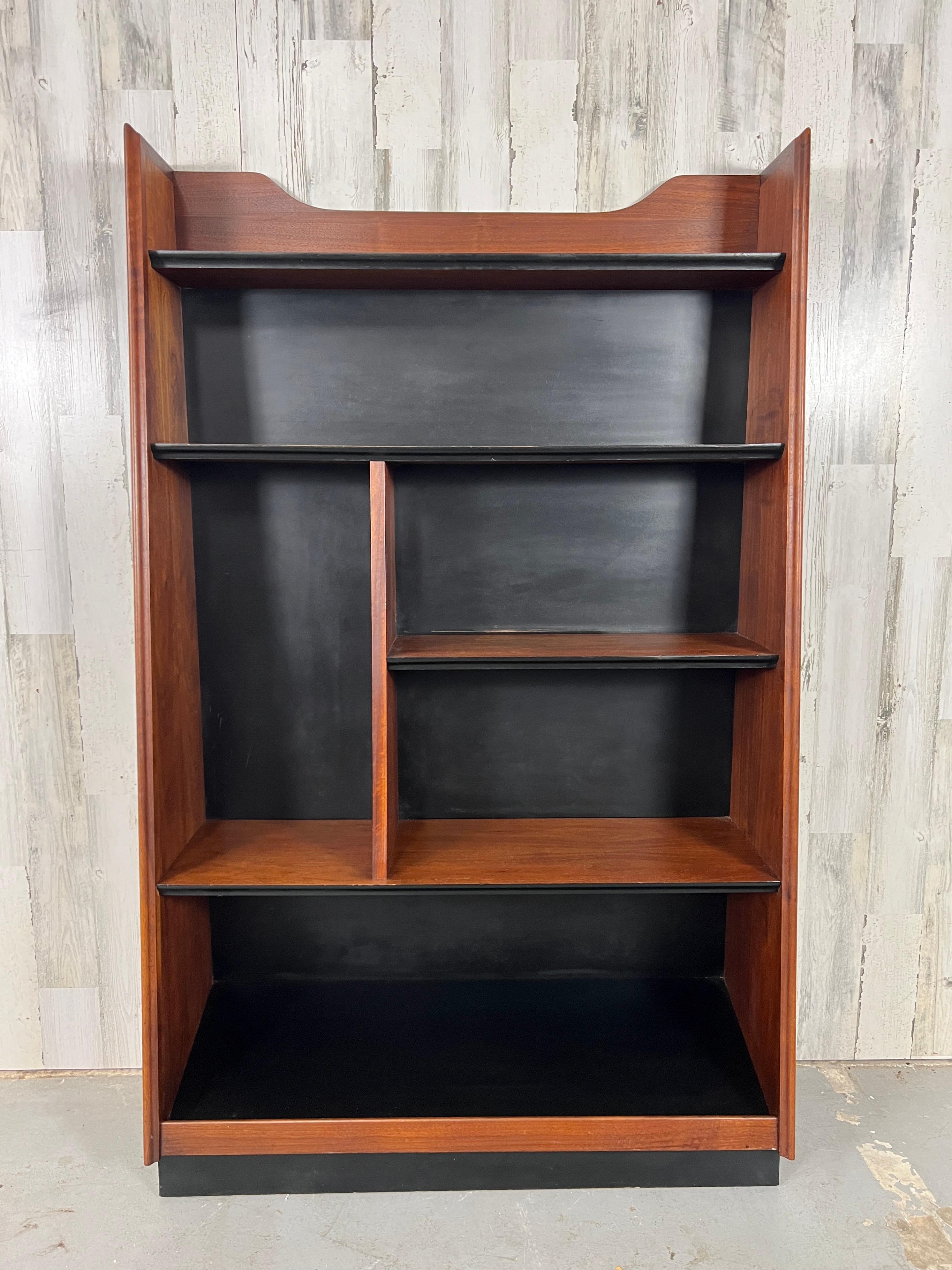 Great tapered design, the bookcase seems like it's leaning against the wall. Designed by Merton Gershun for American of Martinsville. The combination of walnut and black masonite is stunning in any room. the bottom shelf is on a slant to display
