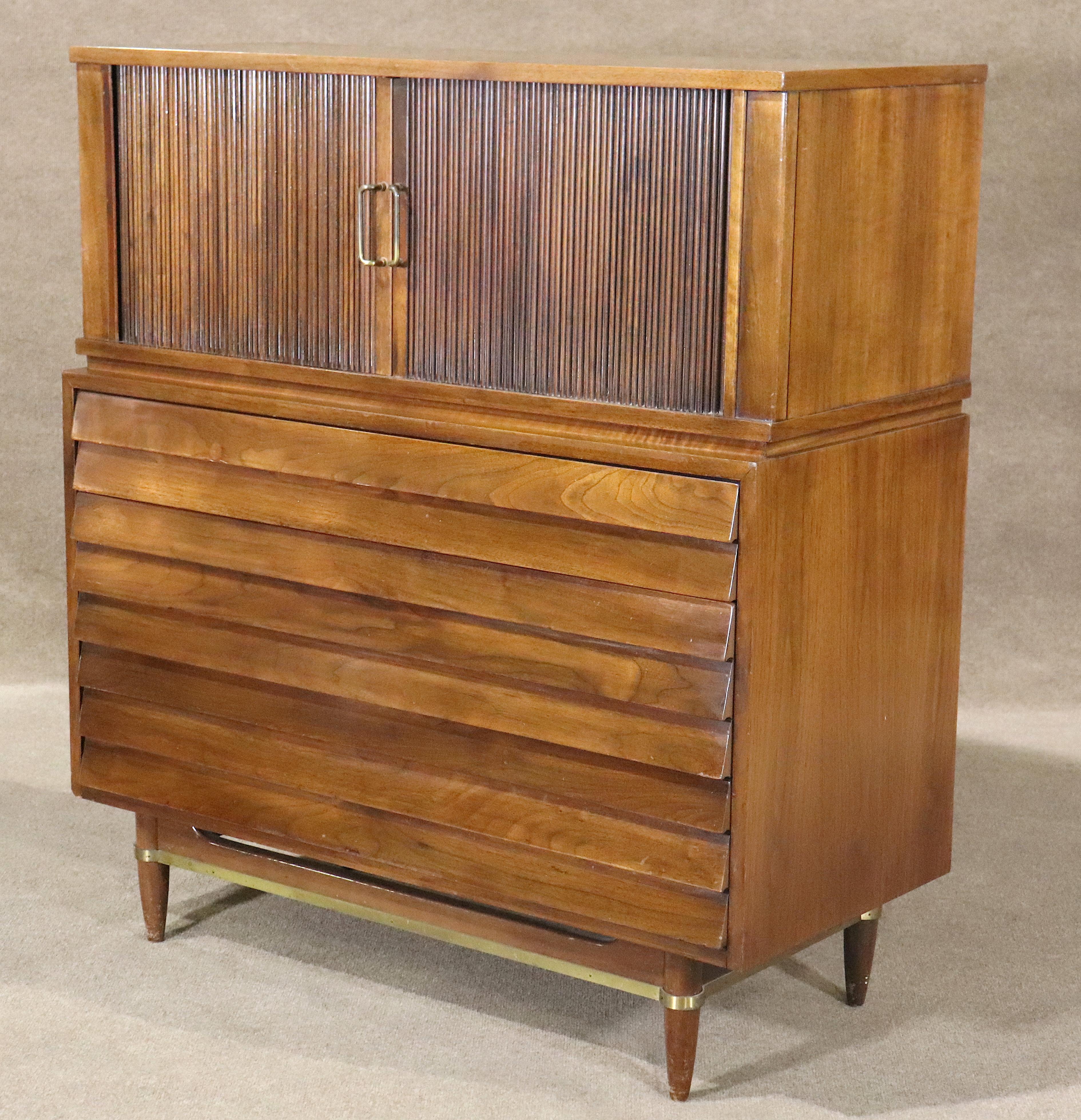 Iconic highchest from the Dania series by Merton Gershun, for American of Martinsville. Features include rich walnut grain, louvered drawers, signature brass accents, and articulated tambour doors, making this best-selling line an American standard