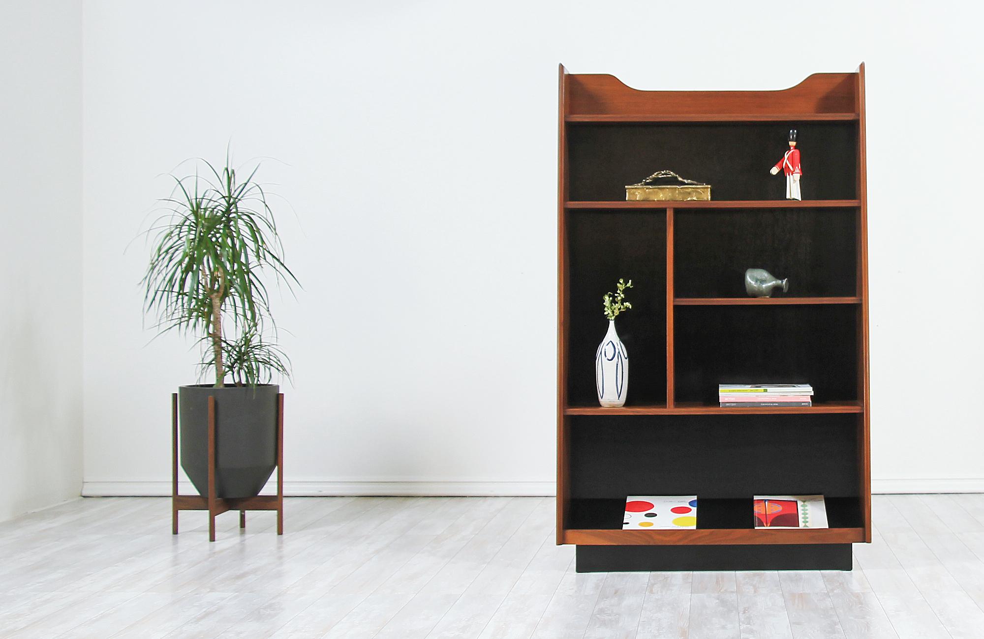 Stunning standing bookshelf designed by Merton L. Gershun for Dillingham in the United States, circa 1960s. This rare design features a walnut wood case with black satin lacquered wood shelving interior striking a tall and angled silhouette to