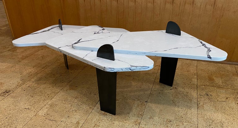 Sculptural Mesa III coffee table constructed of vibrantly veined white quartz stone with laser-cut, blackened steel legs by AdM Bespoke. The multi-level table is raised on varying length legs that project through the stone top via precision