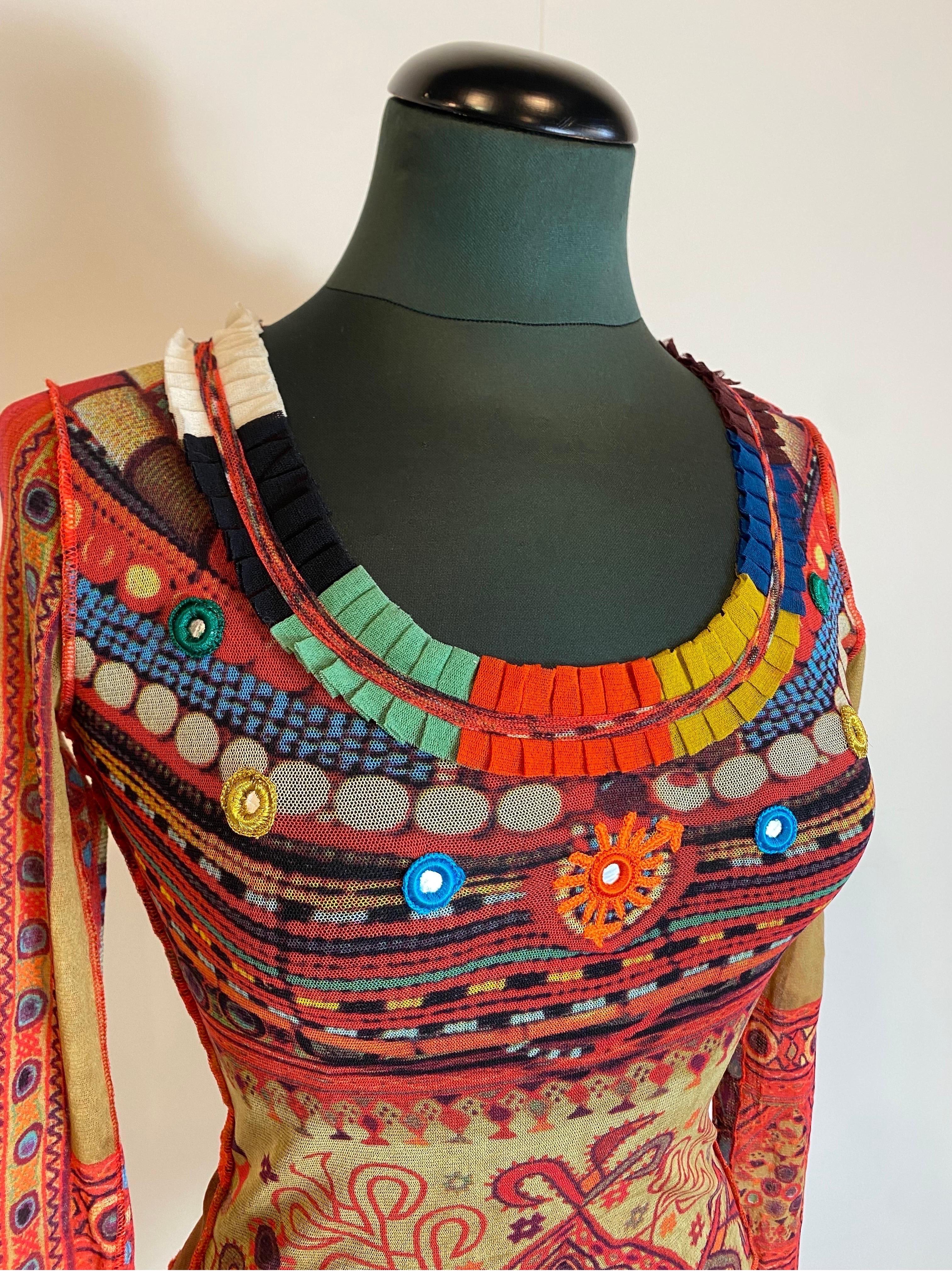 Jean Paul Gaultier Mesh top.
Made of polyamide. 90's.
Soleil collection. Transparent with tribal pattern.
Mirrors with colored embroidered edge as a round neck application.
Open kitchen. Colored ruffle on the neck.
Size S.
Elastic. Sleeve length