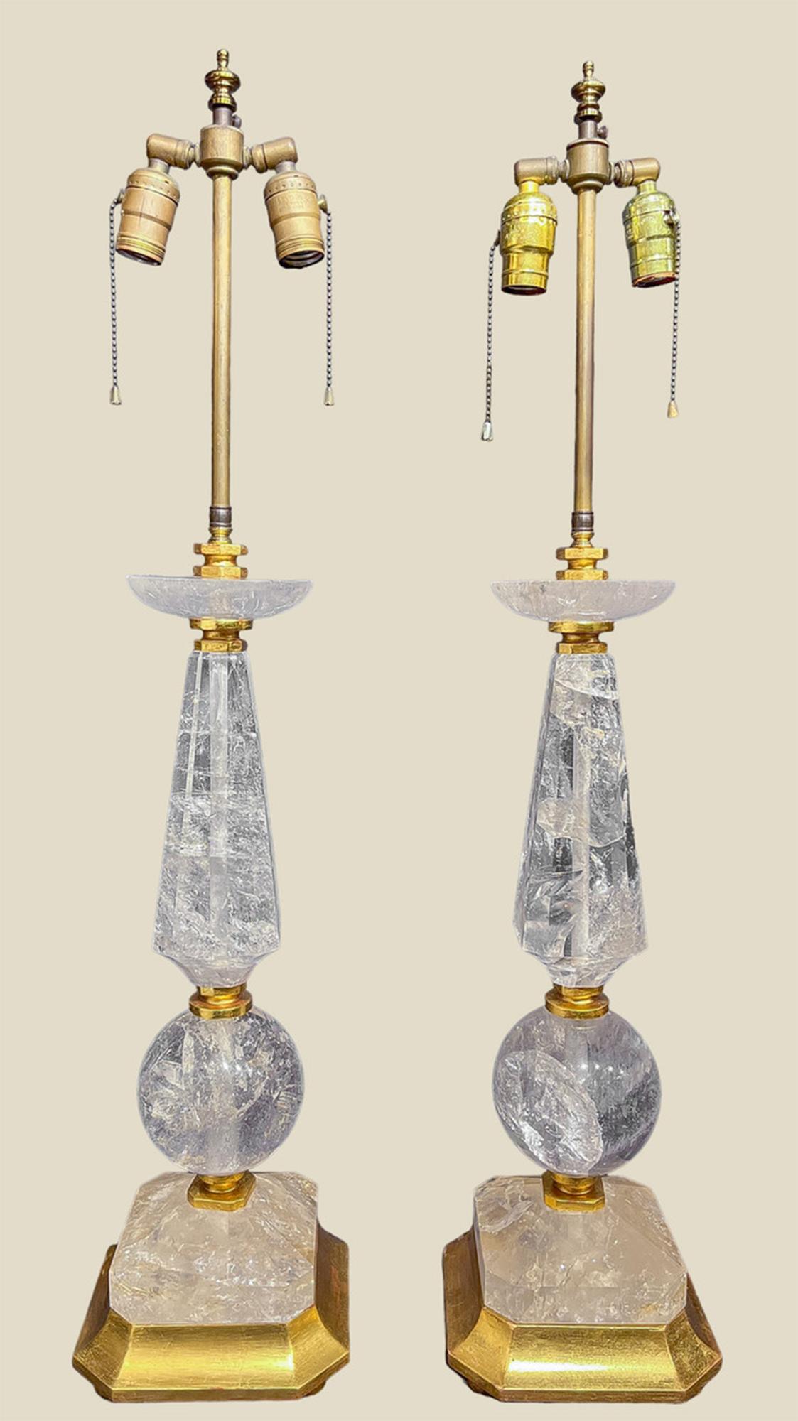 A fine pair of Hollywood Regency or Art Deco style geometric rock crystal lamps with rock crystal cut into spheres, obelisk-esque necks and disks. The large facets within the rock flash rainbows when light is cast through them, creating beautiful