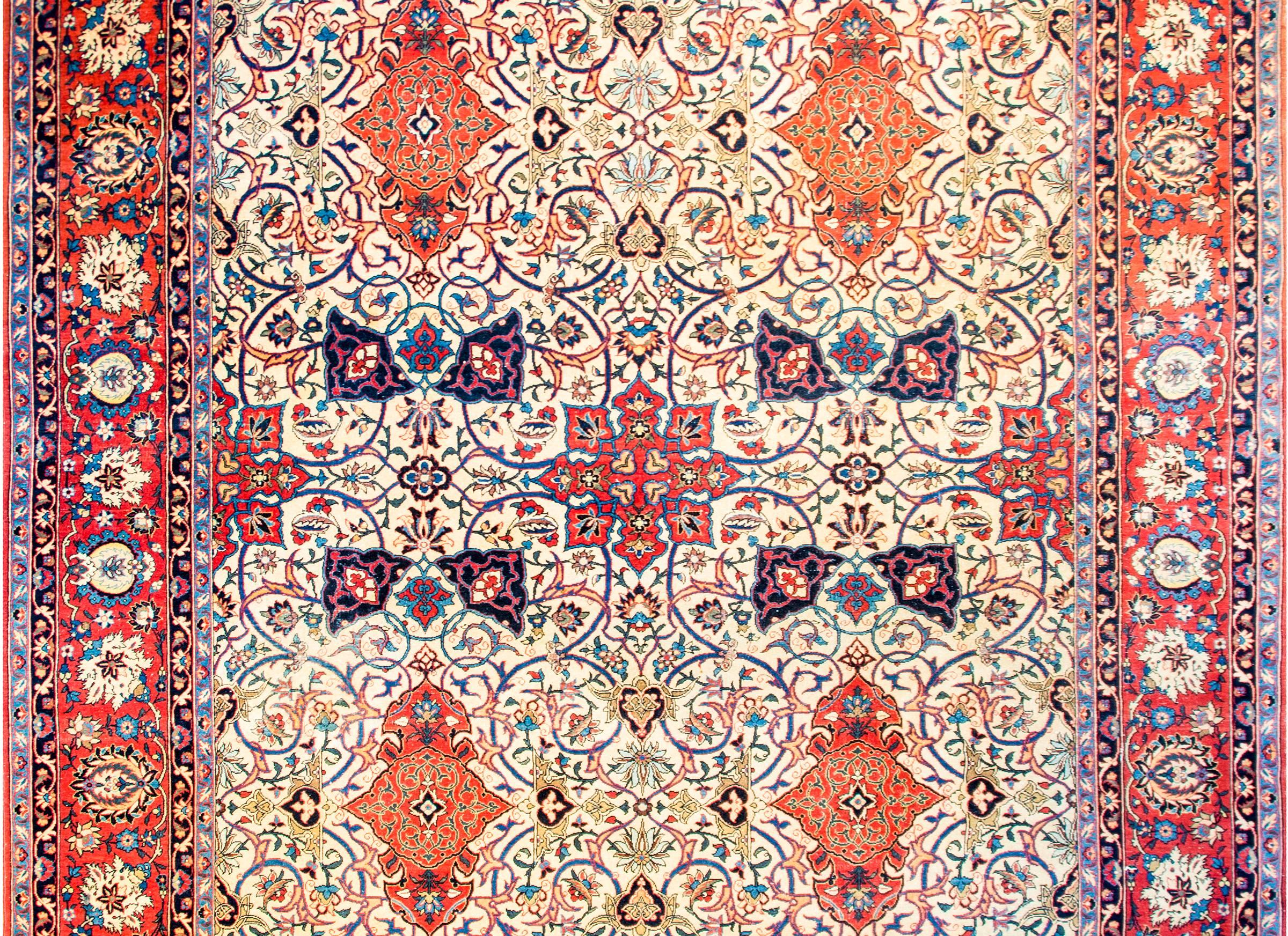 A mesmerizing early 20th century Persian Isfahan rug with an extraordinarily skilled woven pattern of intricately and tightly multicolored floral and scrolling vines, mirrored four ways, on a natural colored wool background. The border is complex