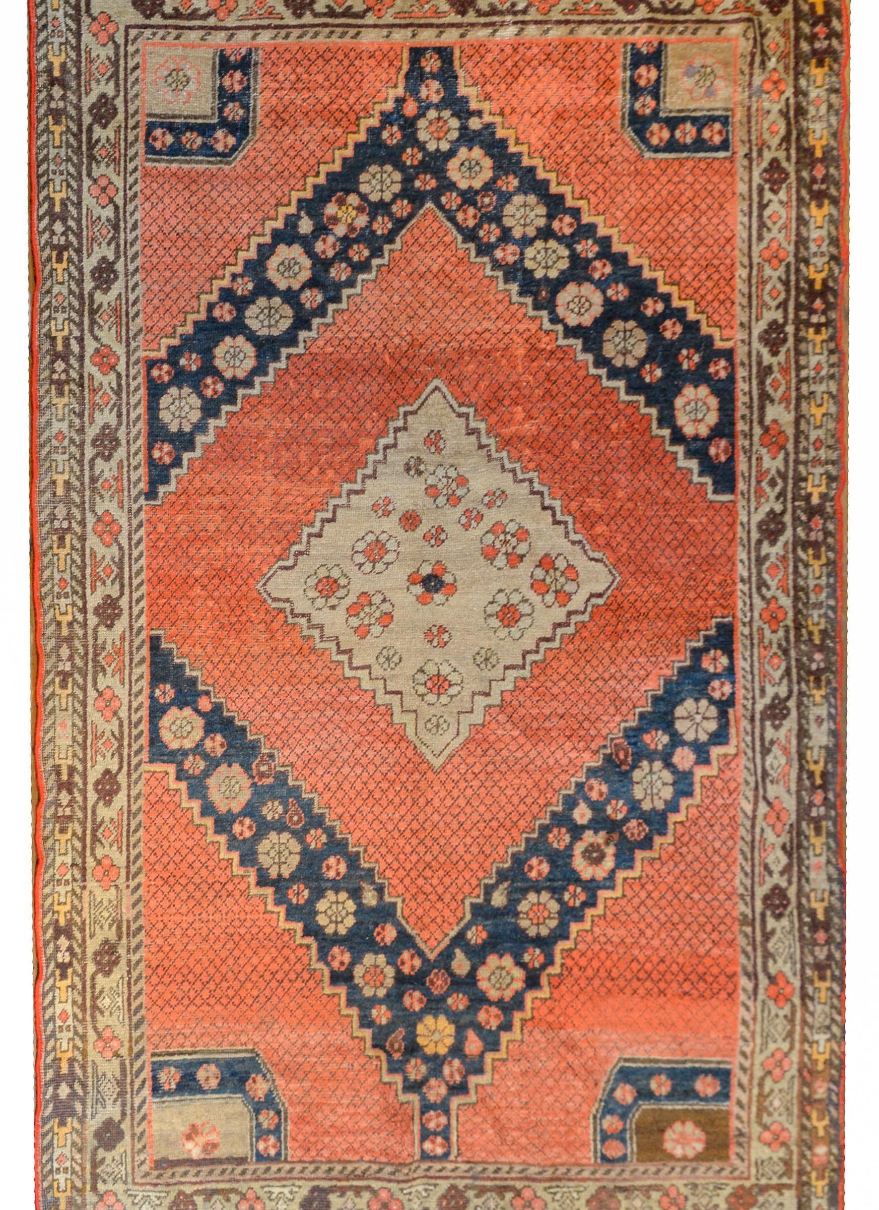 A mesmerizing early 20th century Central Asian Samarkand rug with a large central diamond medallion with a stylized floral pattern woven in coral and beige wool on a coral field with a simple thin lattice pattern, with more stylized flowers on a