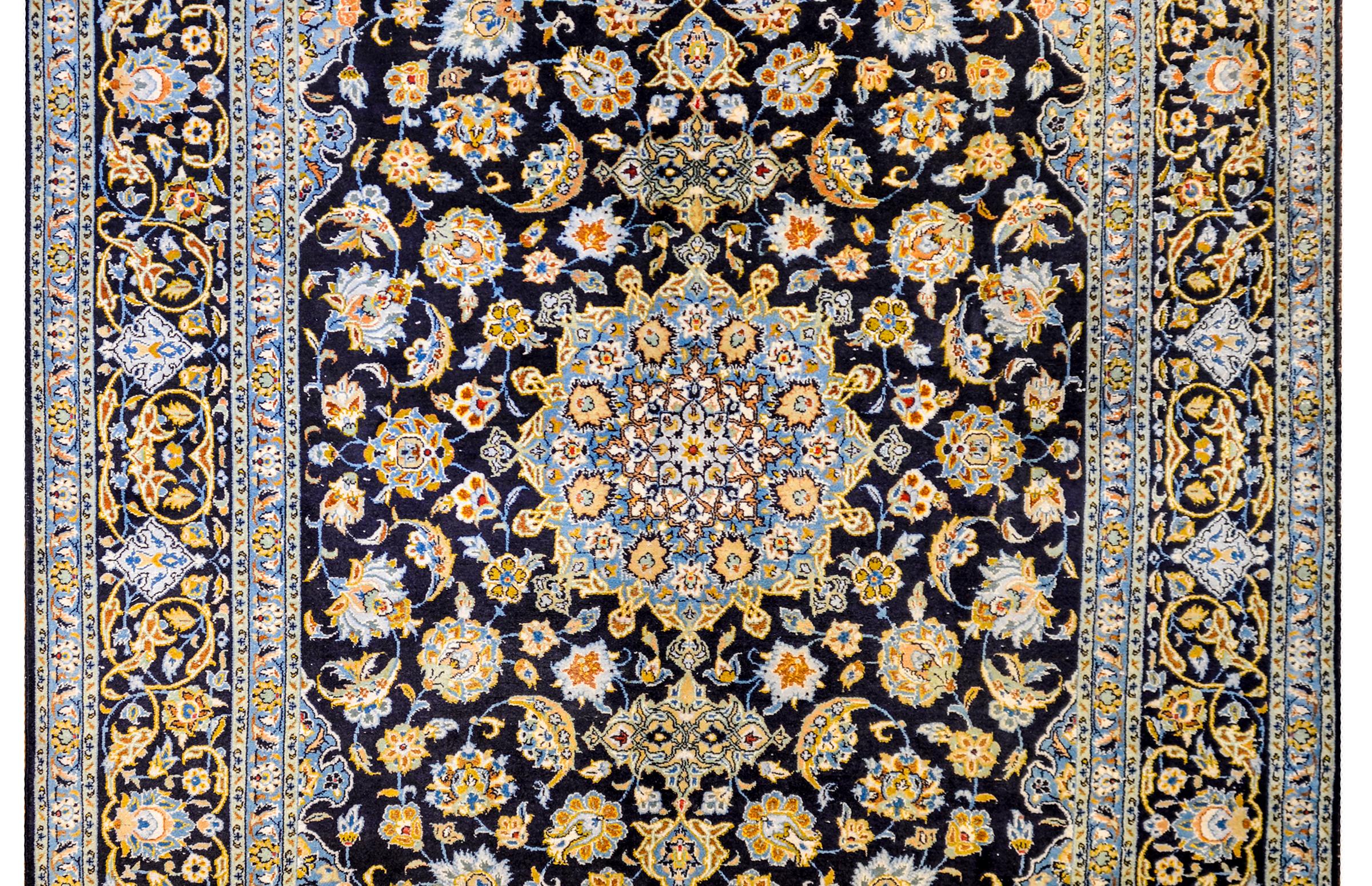 Un tapis persan de Téhéran du début du 20e siècle, merveilleusement envoûtant, avec un grand médaillon floral central au milieu d'un champ de myriades de variétés florales et de vignes feuillues défilantes. La bordure est complexe, et correspond au