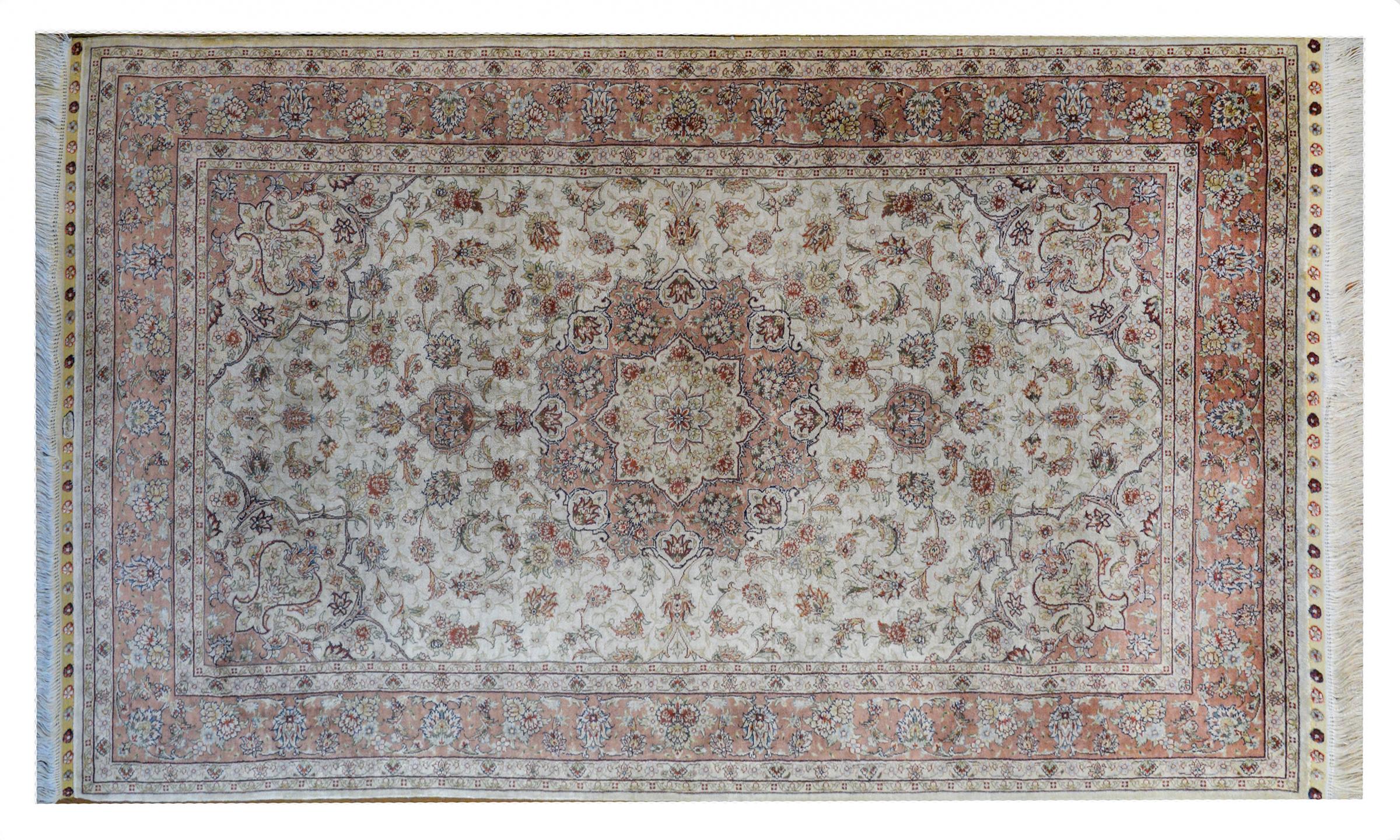 A mesmerizing vintage Egyptian silk Tabriz rug with a beautiful large central floral medallion with myriad flowers and leaves woven in crimson, indigo, yellow, pink, and white silk amidst a field of more flowers and vines against a white background.