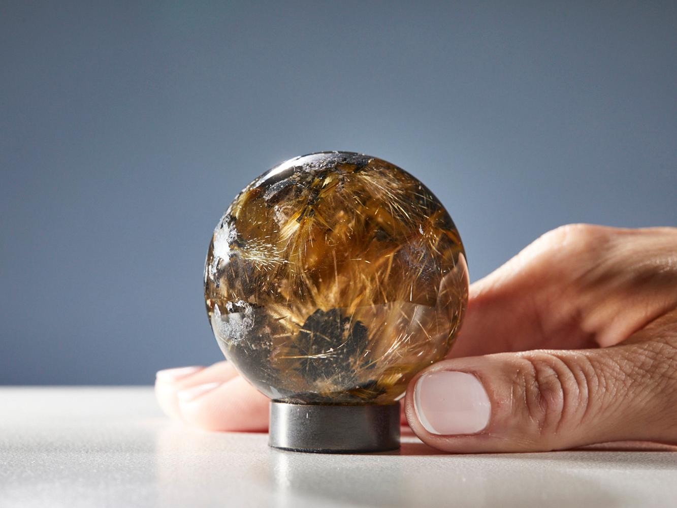Explore the extraordinary allure of this mesmerizing quartz sphere, featuring stunning golden rutile inclusions from Brazil. The perfectly polished surface accentuates the intricate golden threads within, creating a striking visual masterpiece that