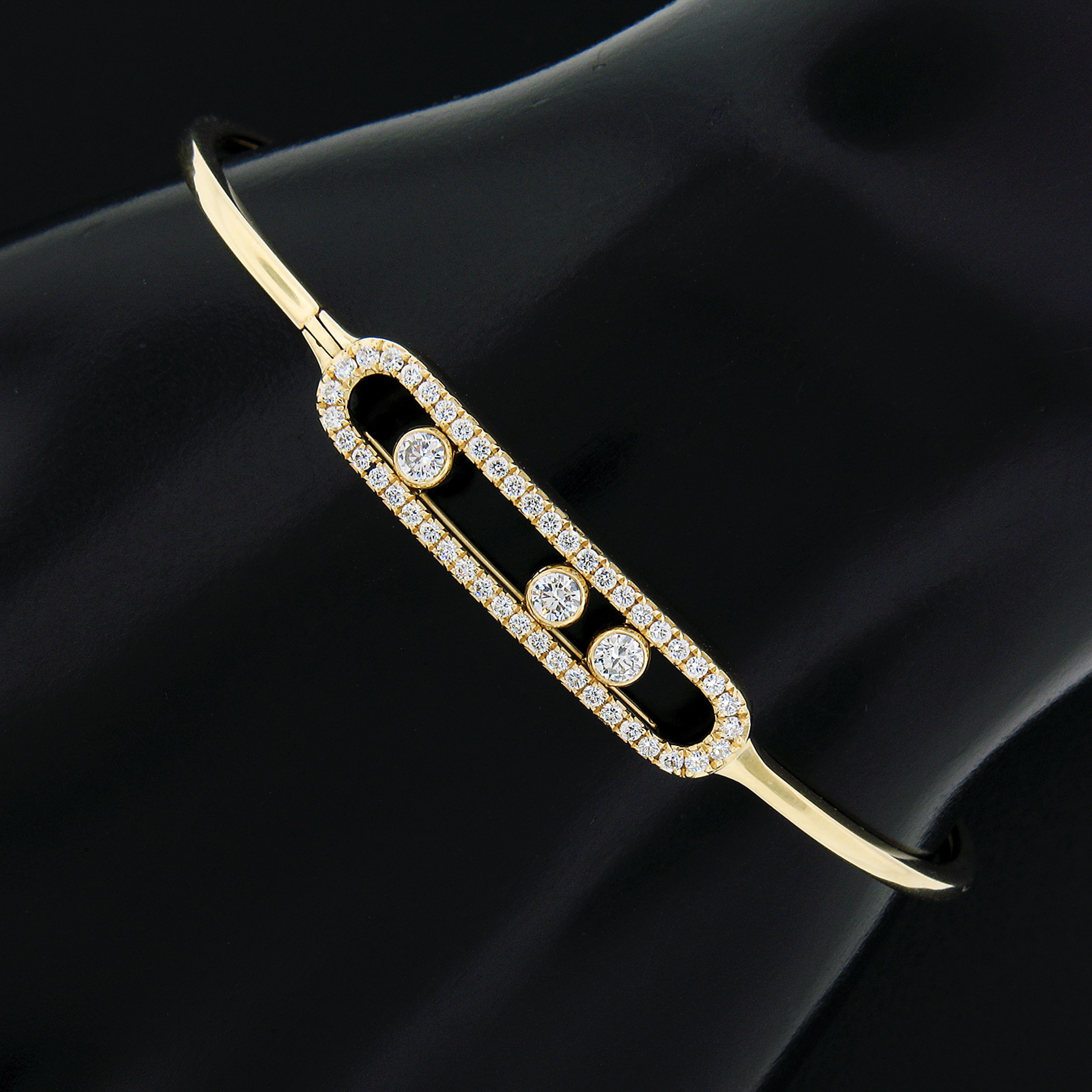 Here we have a beautiful bangle bracelet by MESSIKA that is crafted in solid 18k yellow gold. This beautiful design features a oval open bar at the center that is covered with a numerous pave set diamonds around the frame, the open center have 3