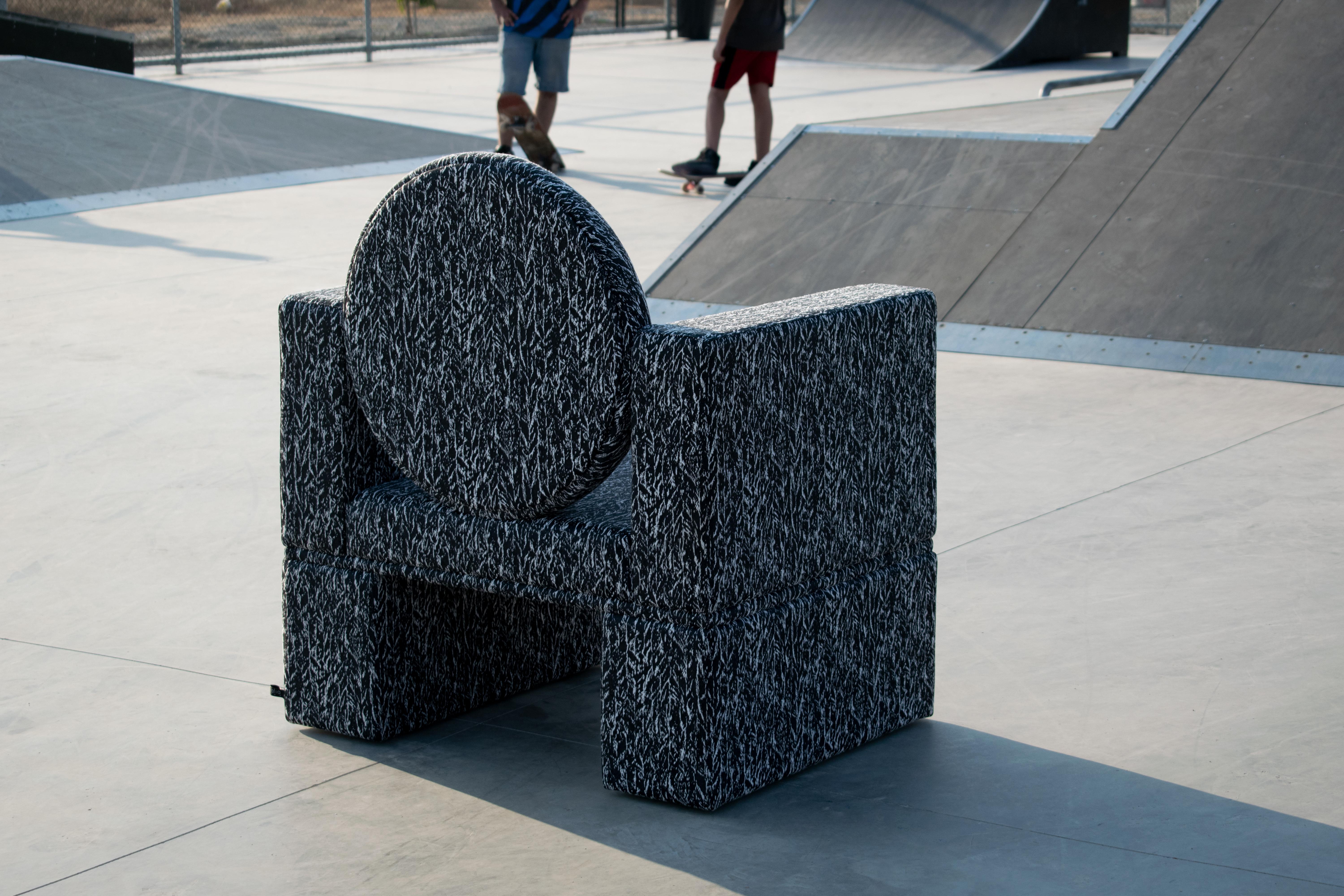 Questa seduta è stata concepita impilando volumi apparentemente puri, dando vita a un cubo articolato che sostiene uno schienale circolare. Ricoperto da un motivo a fantasia in bianco e nero, il design fonde il classicismo primordiale del volume con
