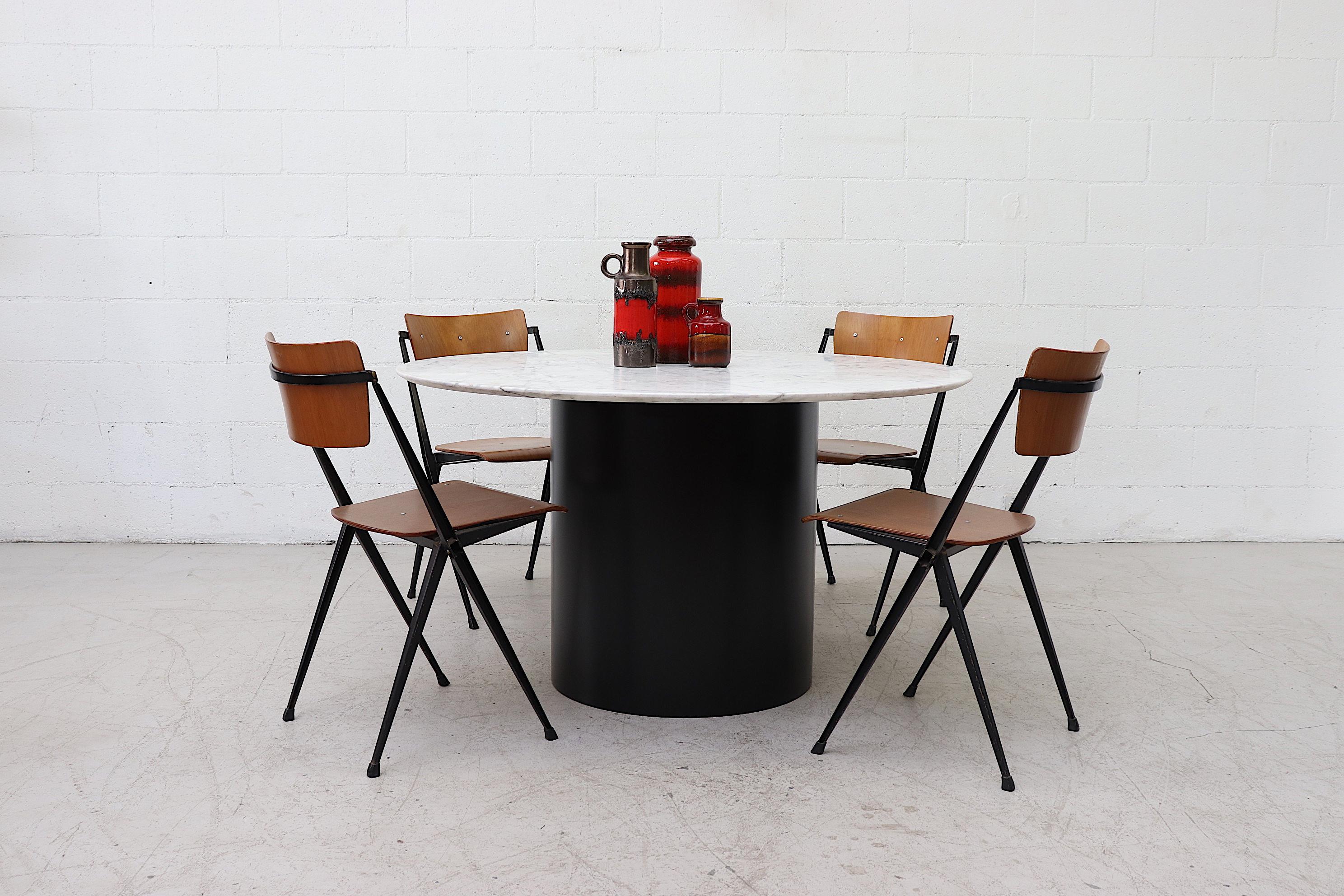Large round marble dining table with reverse beveled edge and newly powder coated black metal base. Shot with Wim Rietveld pyramid stacking chairs (Lu922415501562) and West German ceramic vases. Table top in original condition with visible patina.