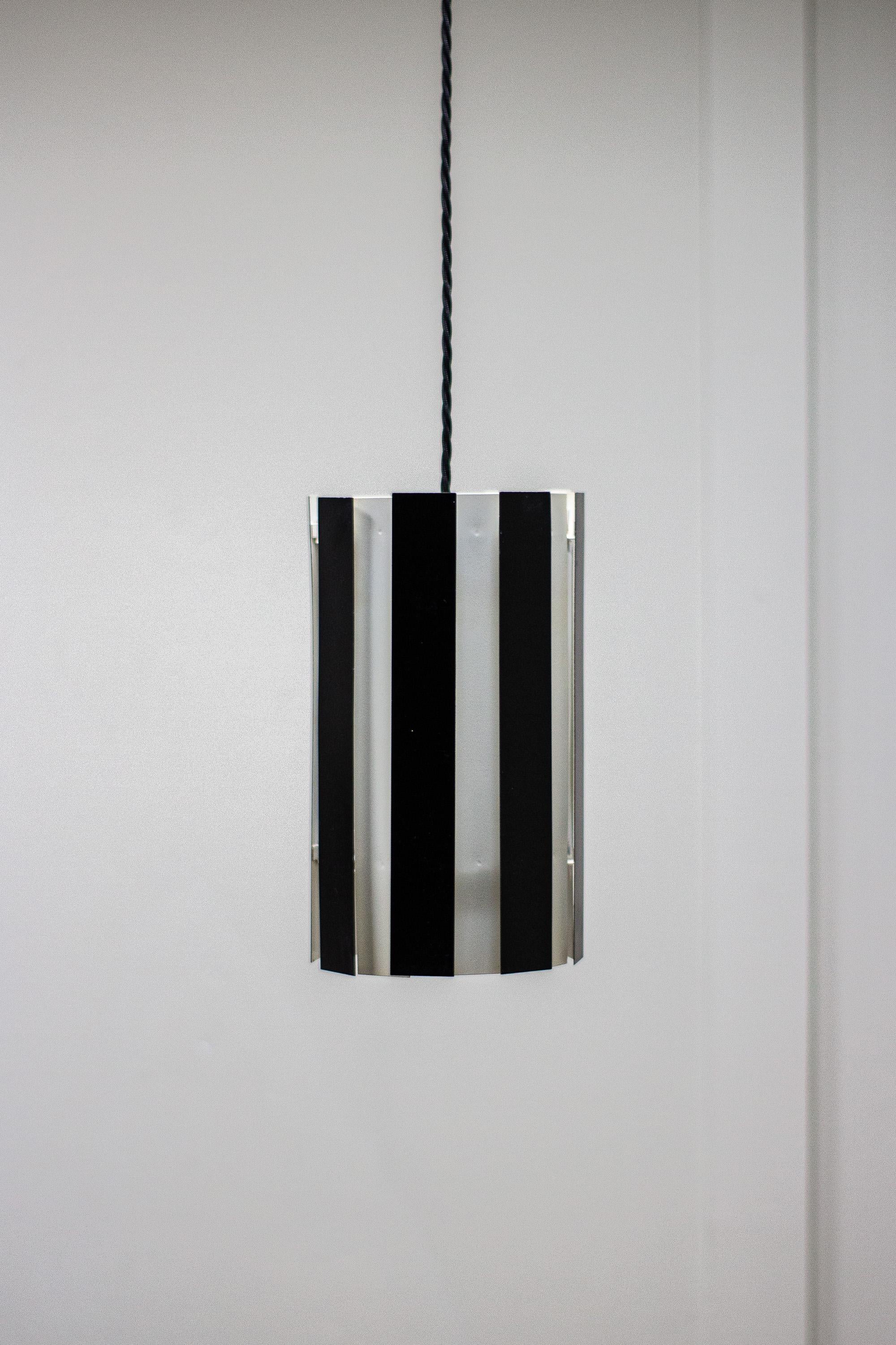 Metal 1960s black and white pendant light.

The black panels on this light allow light to pour through and can be removed for cleaning also. A simple but affective light. Possibly Danish. 

Fully rewired, with new bulb holder and PAT tested.