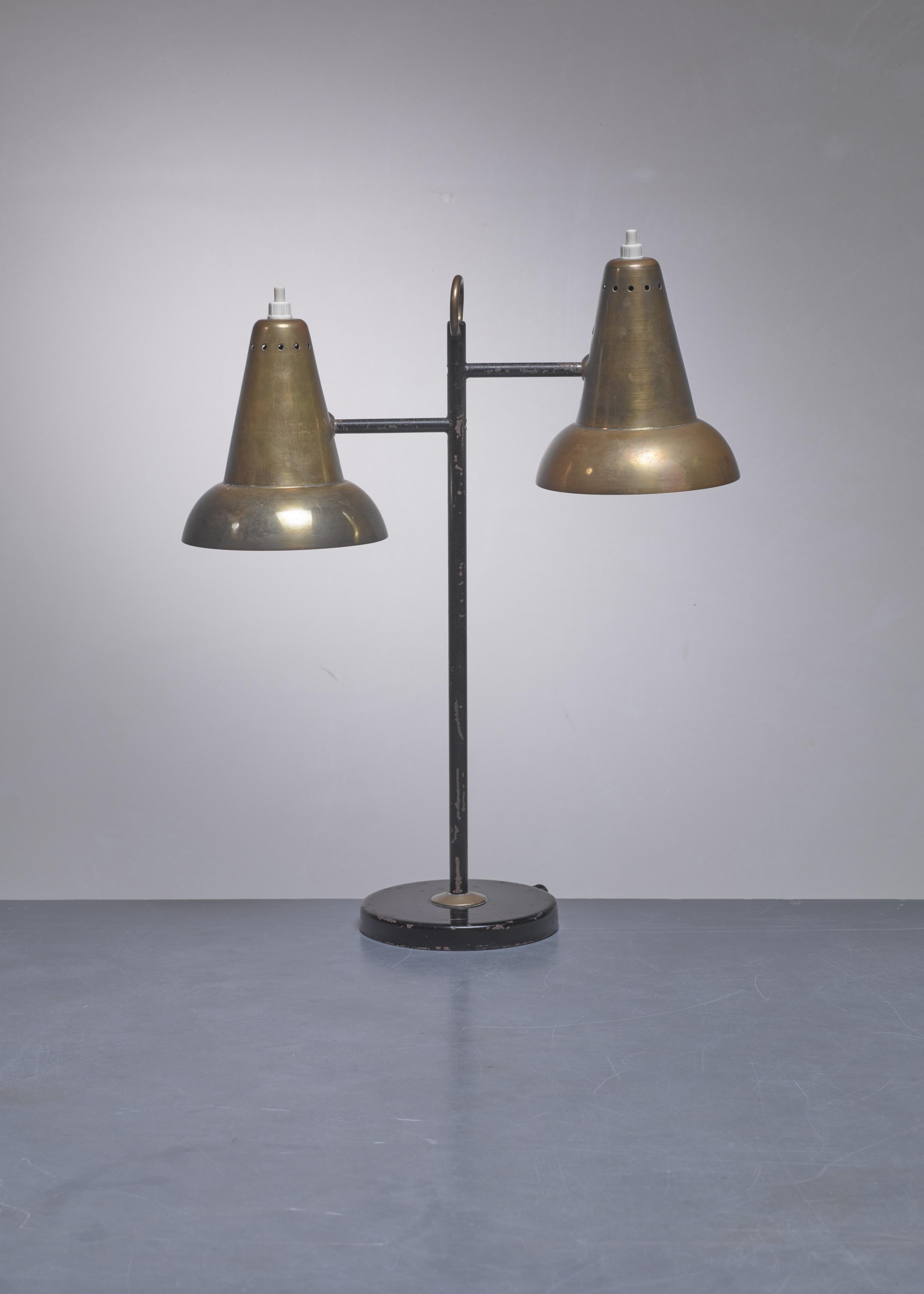 A French Modernist table lamp made of black lacquered metal and brass. The lamp has two adjustable hoods, connected with a ball joint. The design is reminiscent of the work of Jacques Biny.