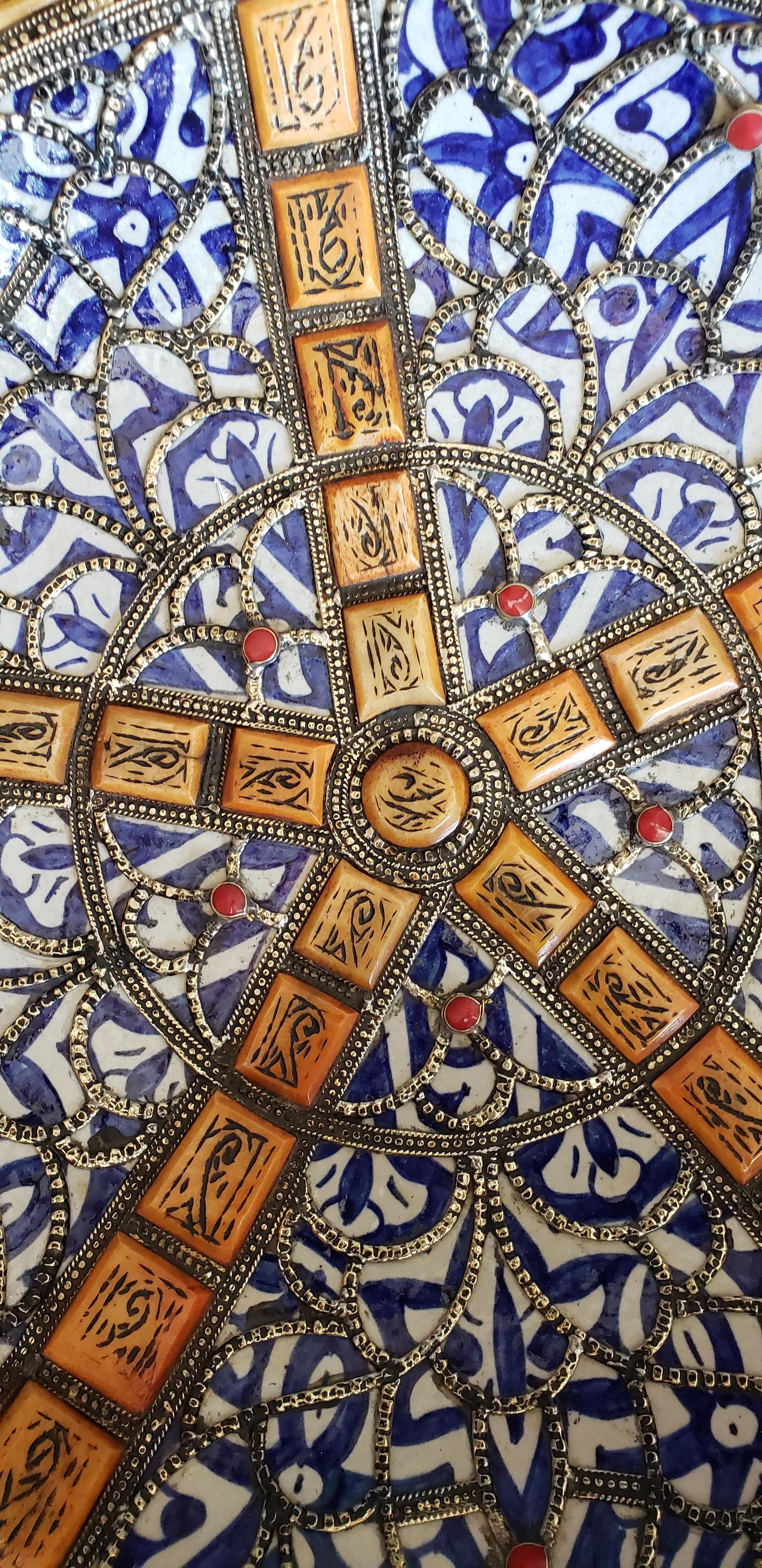A rare or one of a kind exquisite Moroccan plate / charger for decoration purpose only. This plate is hand painted in blue and white and inlaid with metal. Henna dyed Camel bone fragments throughout. This plate would be a great add-on to any décor.