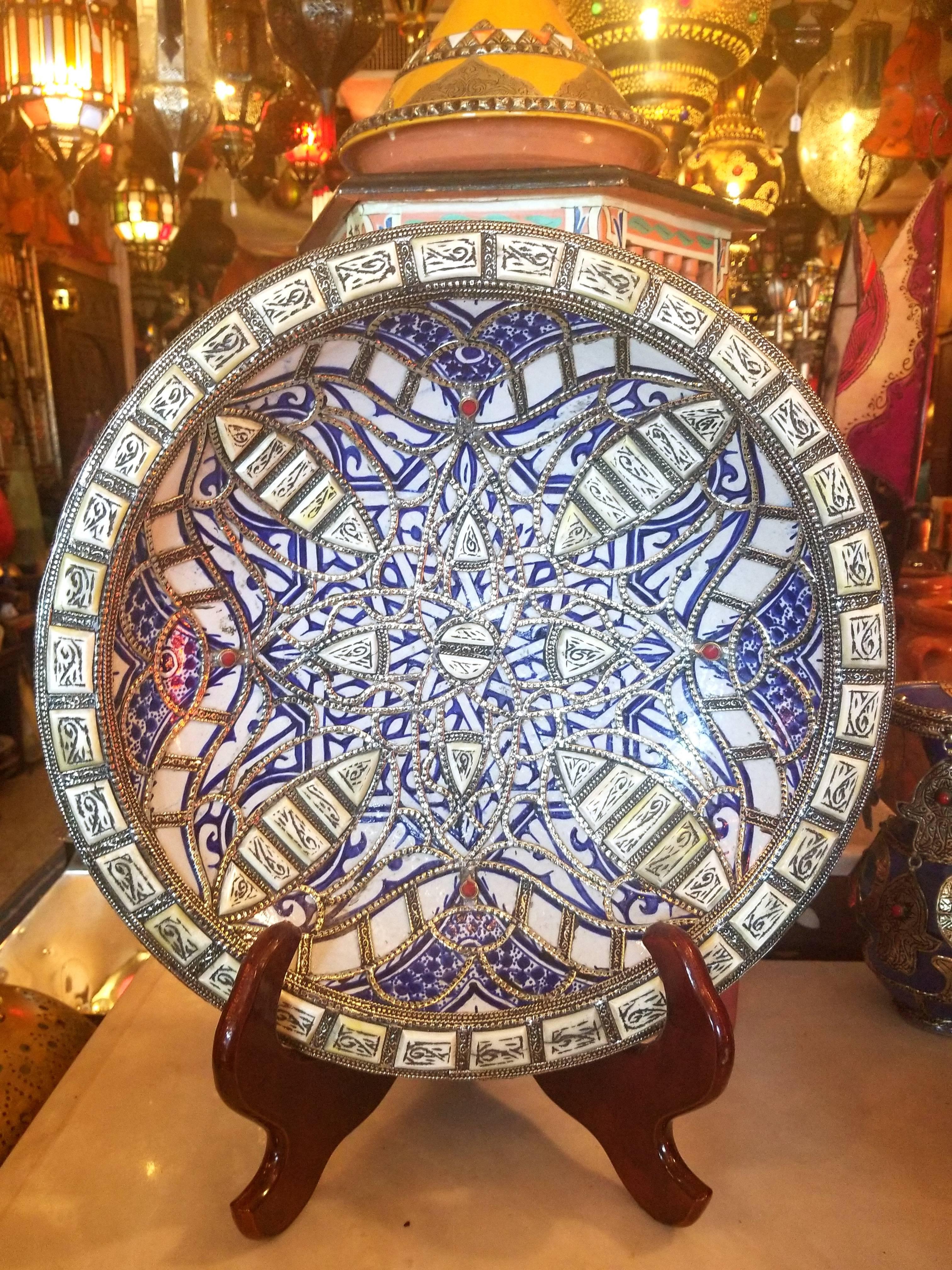 A rare or one of a kind exquisite Moroccan plate / charger for decoration purpose only. This plate is hand-painted in blue and white, and inlaid with metal. Henna dyed Camel bone fragments throughout. This plate would be a great add-on to any décor.