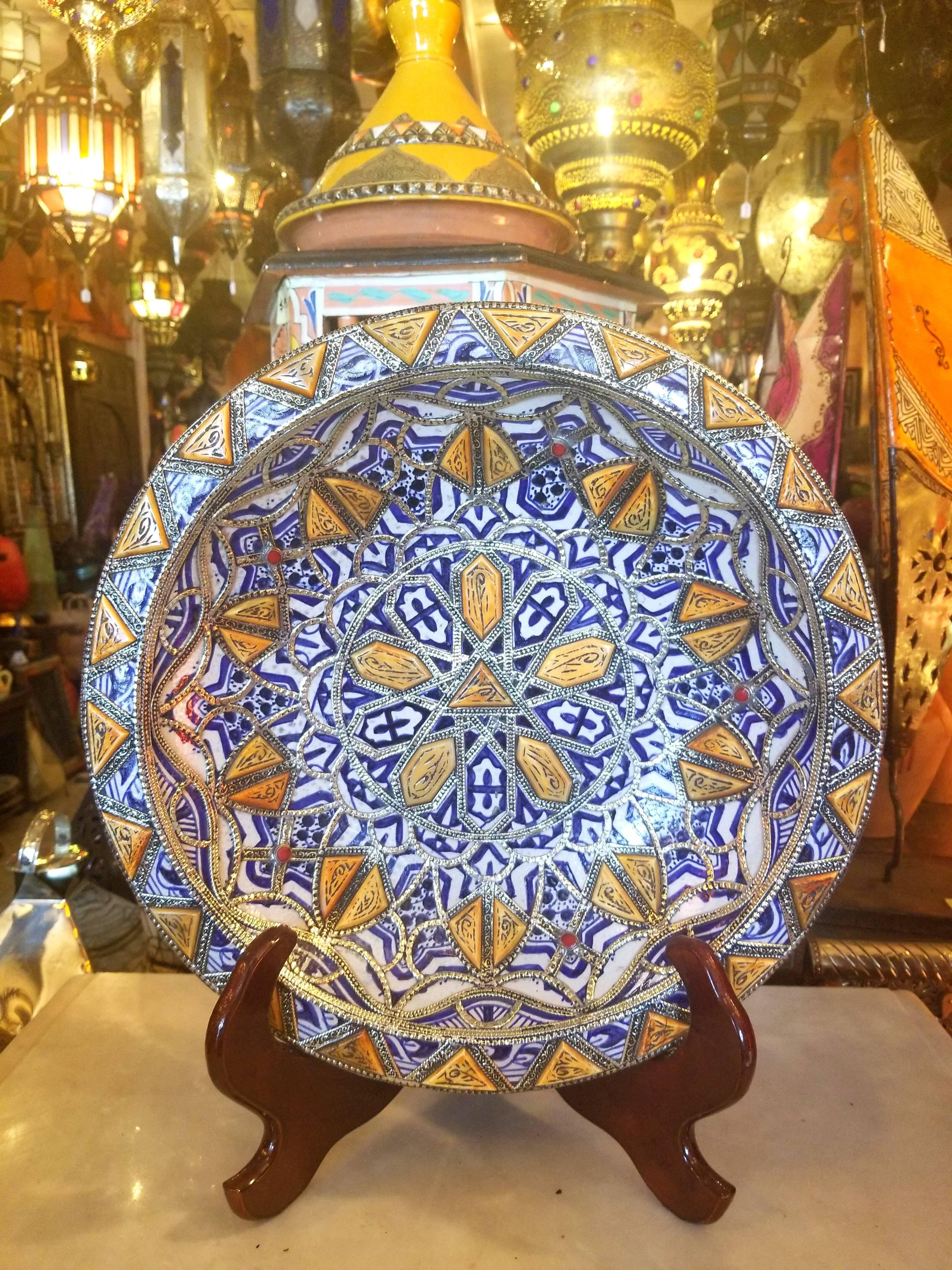 A rare or one of a kind exquisite Moroccan plate / charger for decoration purpose only. This plate in hand-painted in blue and white, and inlaid with metal. Henna dyed Camel bone fragments throughout. This plate would be a great add-on to any décor.