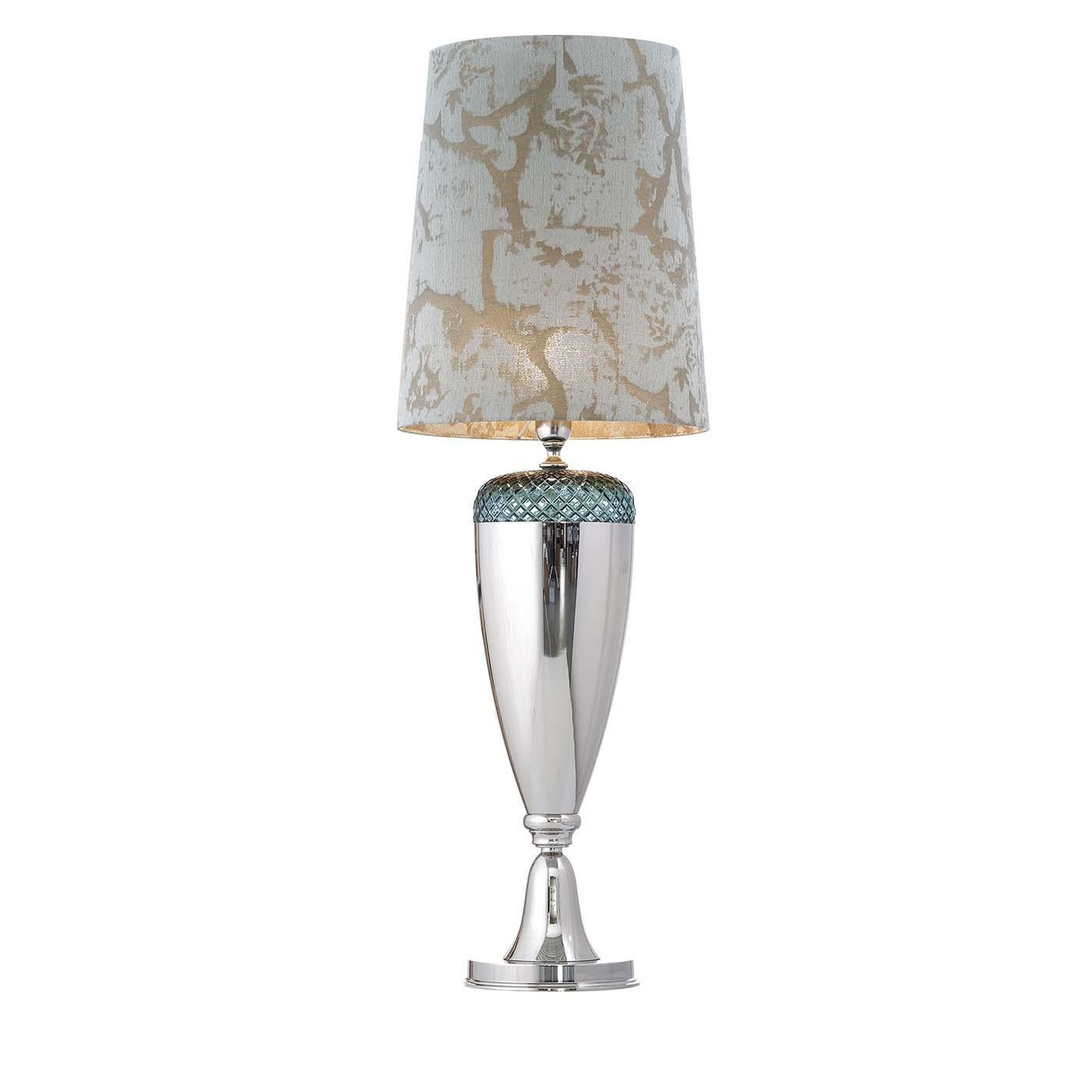 This stunning table lamp combines the smooth and glossy surface of a sinuous base in metal with its top, adorned with a superb handcut, 24 lead Italian crystal that boasts an aquamarine-green color and a geometric diamond-shaped texture. The shade's