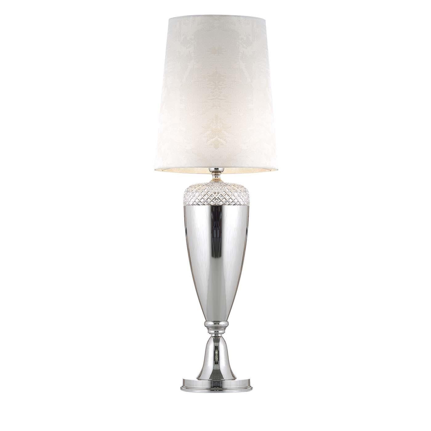 This stunning table lamp combines the smooth and glossy surface of a sinuous base in metal with its top, adorned with a superb handcut, 24 lead Italian crystals. The shade's structure in PVC is covered in an elegant fabric from the Ruskin collection