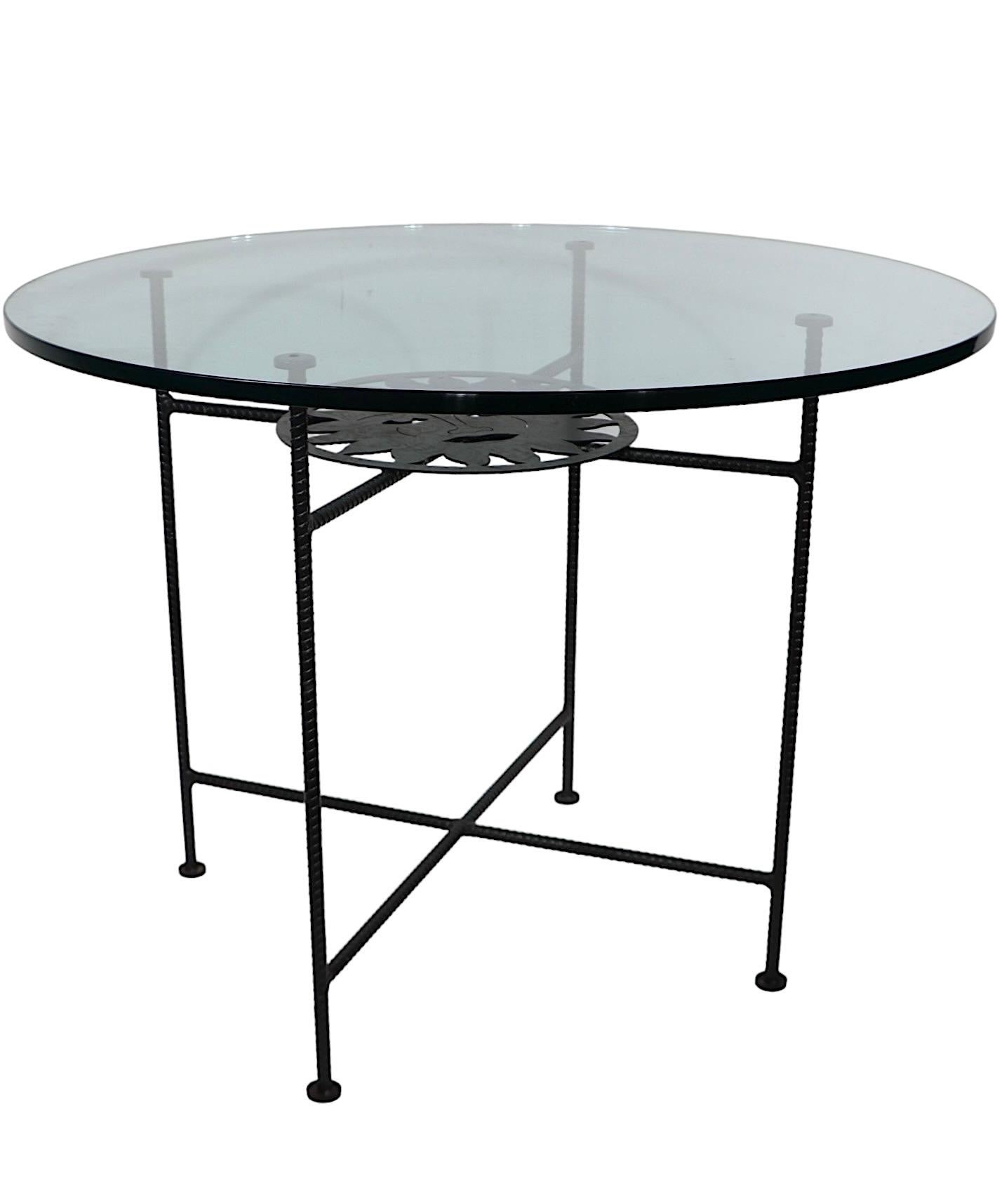  Chic glass and metal dinette cafe style dining table, made in Mexico circa 1990's. The table features a stylized sun face of cut metal, mounted on the rebar frame, which supports the thick circular tempered glass top. 
 This example is in 