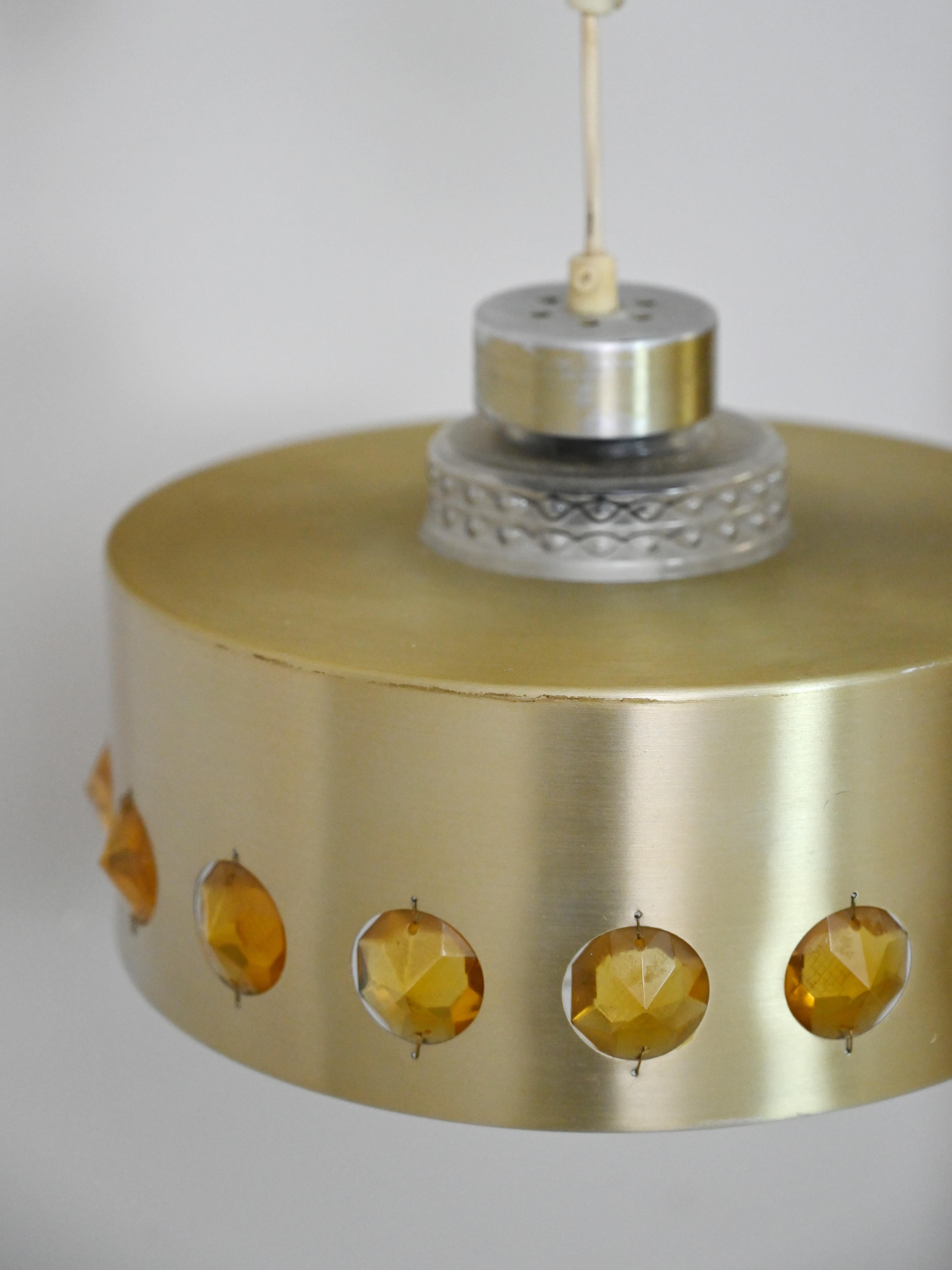 Original Vintage-Lampe aus den 1960er Jahren.

Eine einzigartige Retro-Lampe, die aus zwei Teilen besteht.

Der innere Lampenschirm ist aus Kristall, der äußere aus goldenem Metall mit eingebetteten bernsteinfarbenen Kunststeinen.

Es ist ein