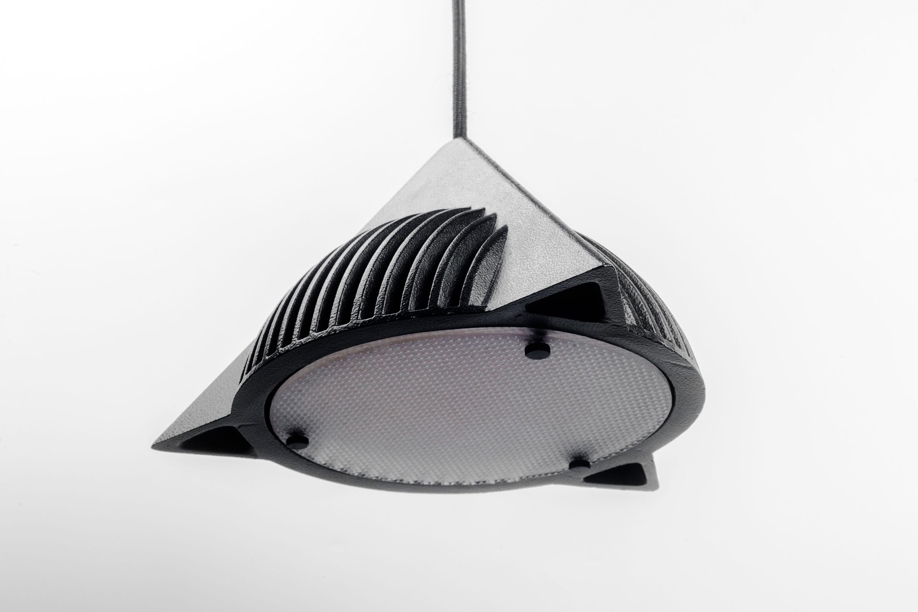 Black metal pyramid pendant with glass diffuser designed by Ron Rezek in the 1990s. A cast iron half sphere within a pyramid, floating like a UFO. Primary geometric shapes combined in a post-modern style that feels like a more elegant, mature