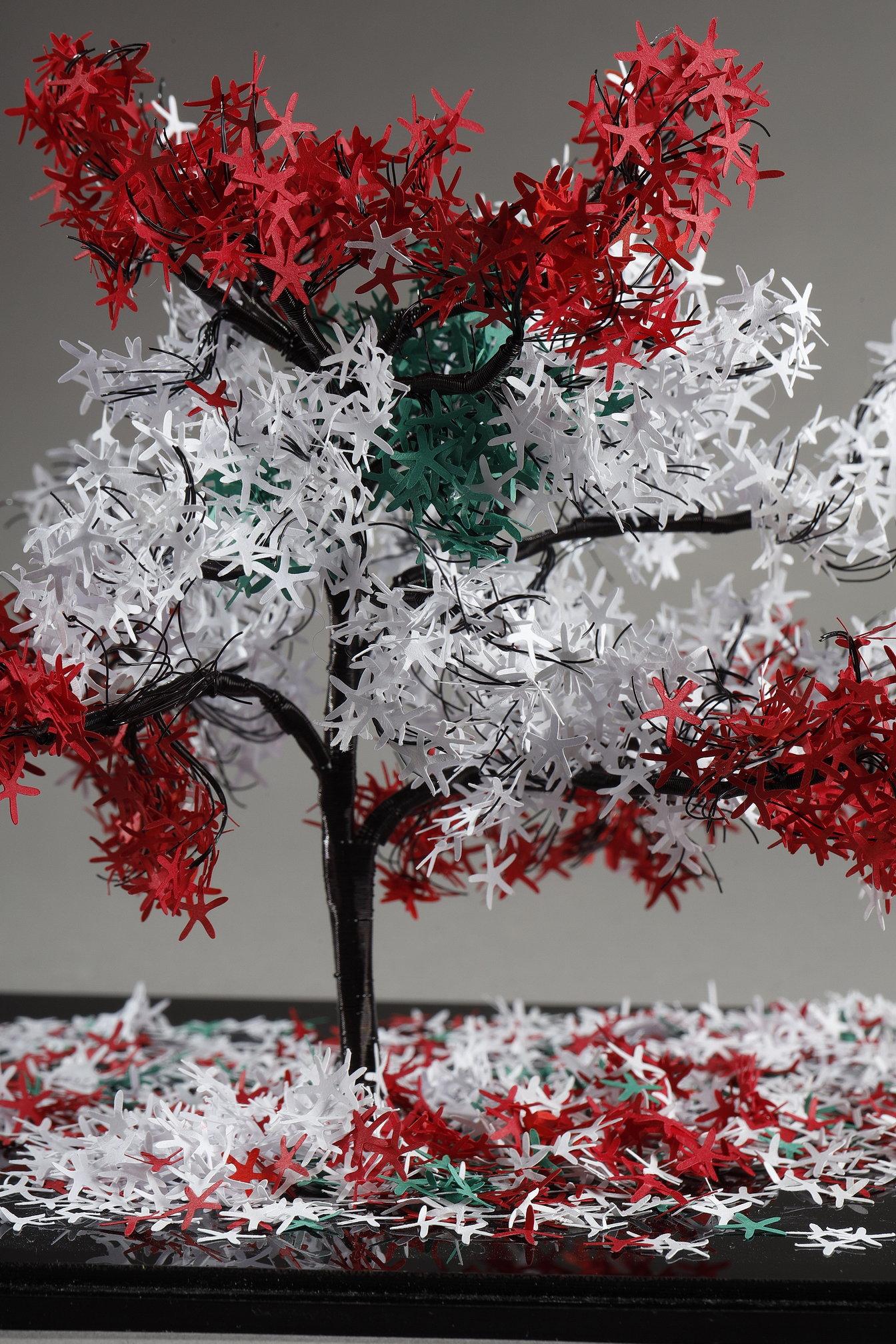 Questo pezzo unico dell'artista libanese Nayla Tabet è una scultura ad albero che combina fili metallici di alta qualità e carta finemente tagliata nei colori del Libano (rosso, bianco, verde), dando vita a un'opera unica nel suo genere. L'artista