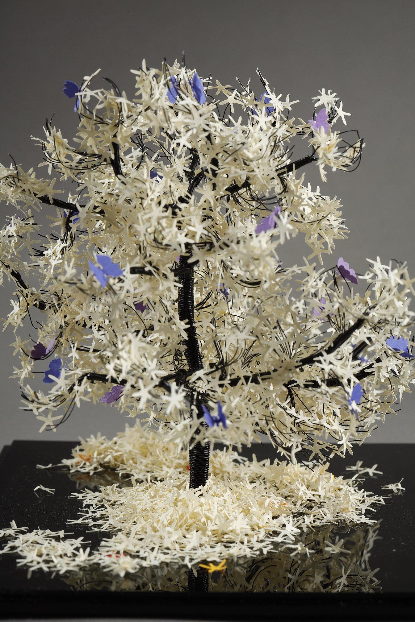 Questo pezzo unico dell'artista libanese Nayla Tabet è una scultura ad albero che combina fili metallici di alta qualità e carta bianca e viola finemente tagliata, dando vita a un'opera unica nel suo genere. L'artista ama esplorare il contrasto tra