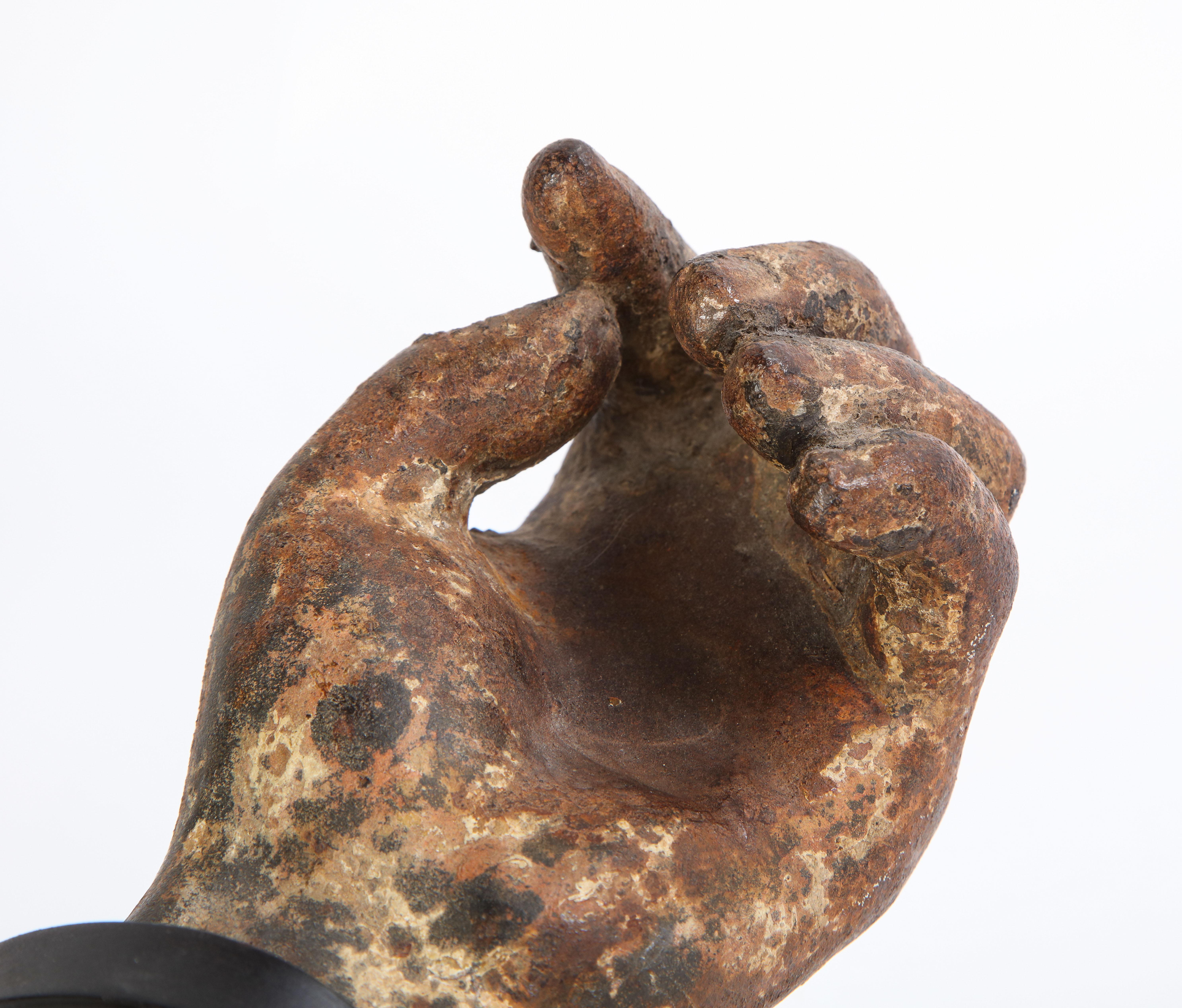 This is a sculptural fragment of a cast, patinated metal arm elevated on a black-painted metal stand. The lifelike metal arm fragment makes for a true conversation starter and would be an attractive centerpiece on a sideboard or hall table. Dating