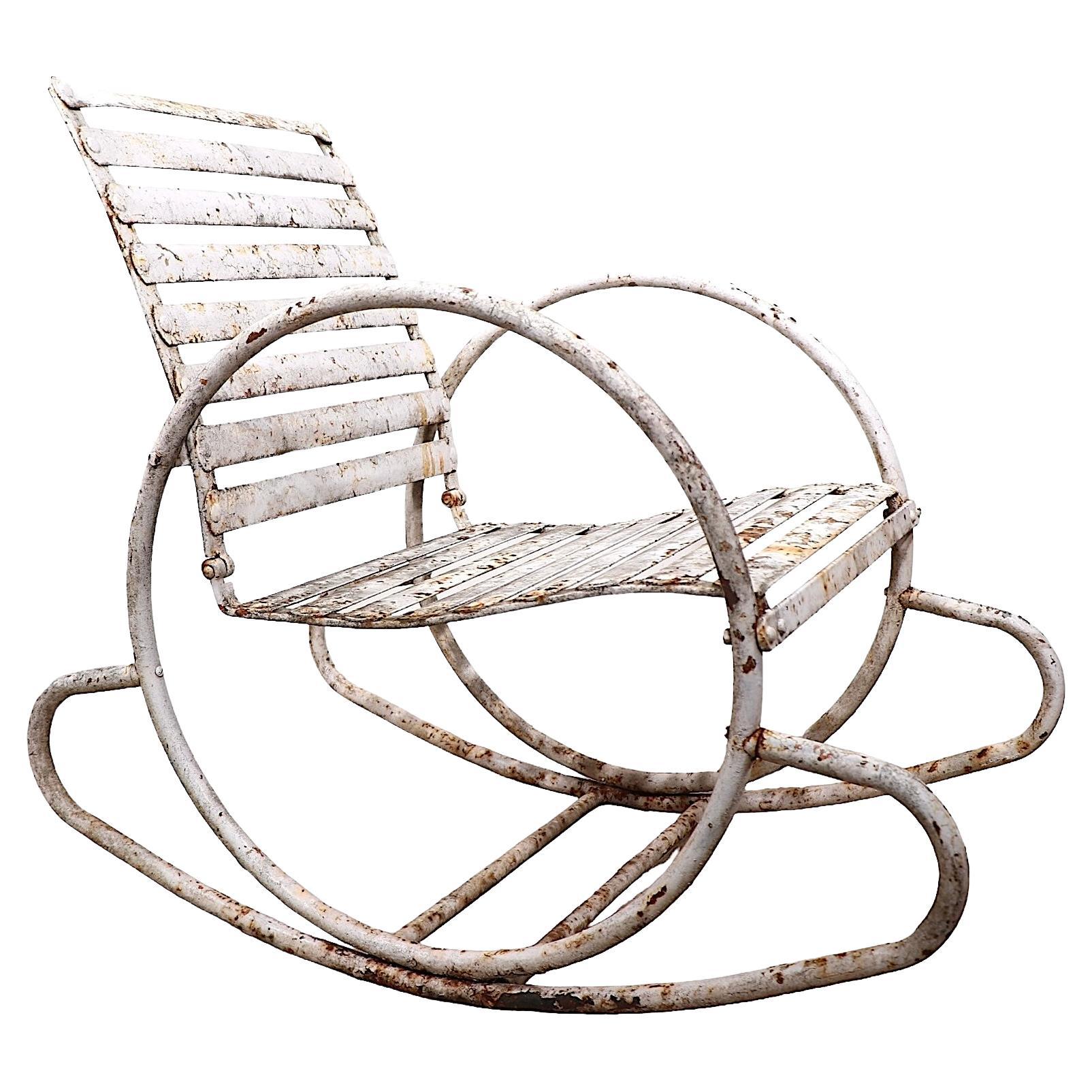 Elegante mecedora metálica Art Decó de exterior para jardín, patio o piscina, hecha a mano  por The Cincinnati Artistic Wrought Iron Works Company, hacia 1930. La silla tiene un armazón tubular con brazos y patas circulares continuas opuestas, con