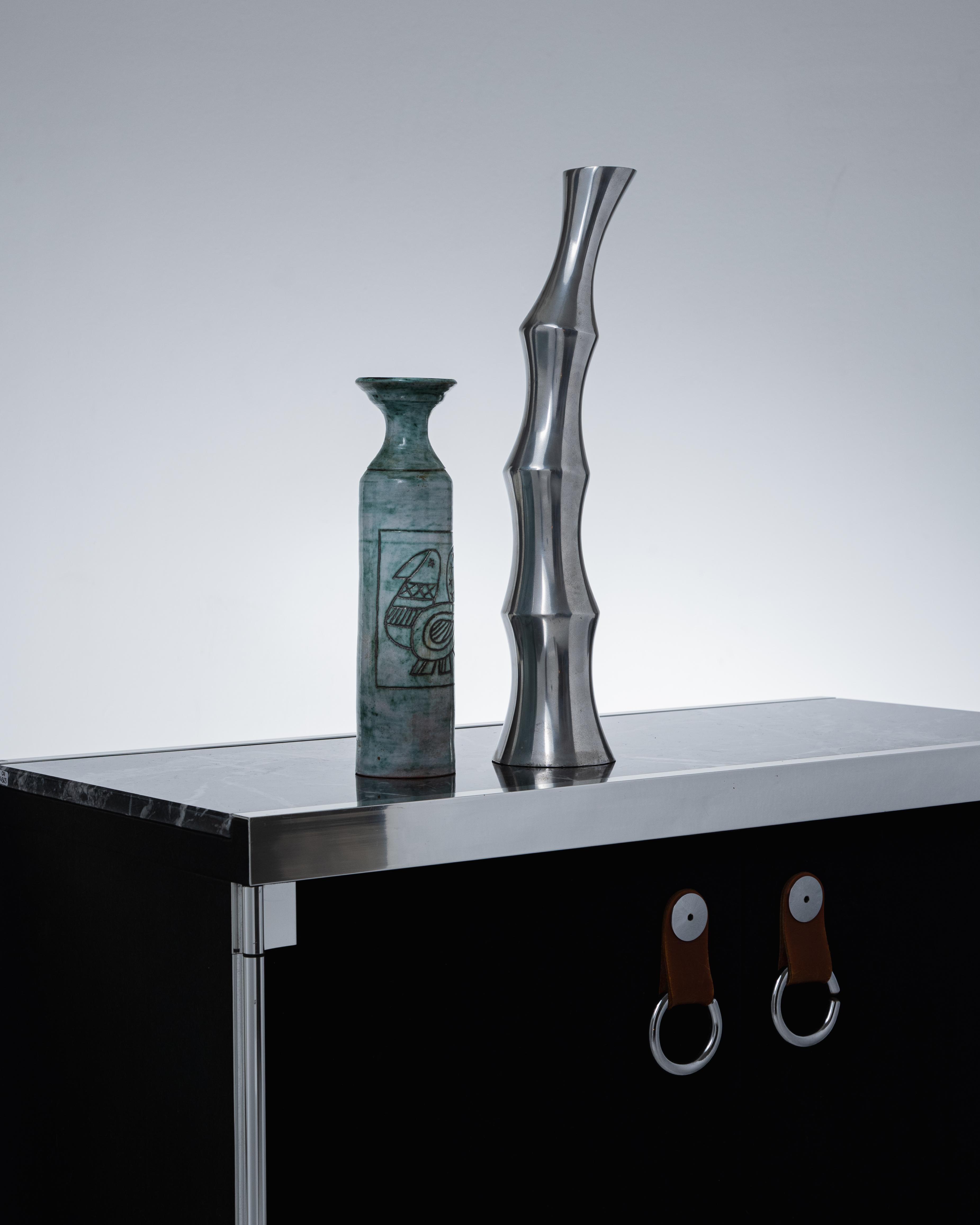 Vase en métal en forme de bambou, années 1970. Pièce emblématique du style moderniste, son design vertical, ponctué d'arêtes, allie formes organiques et architecturales. Très bon état.
LP5851-53 - LP5855