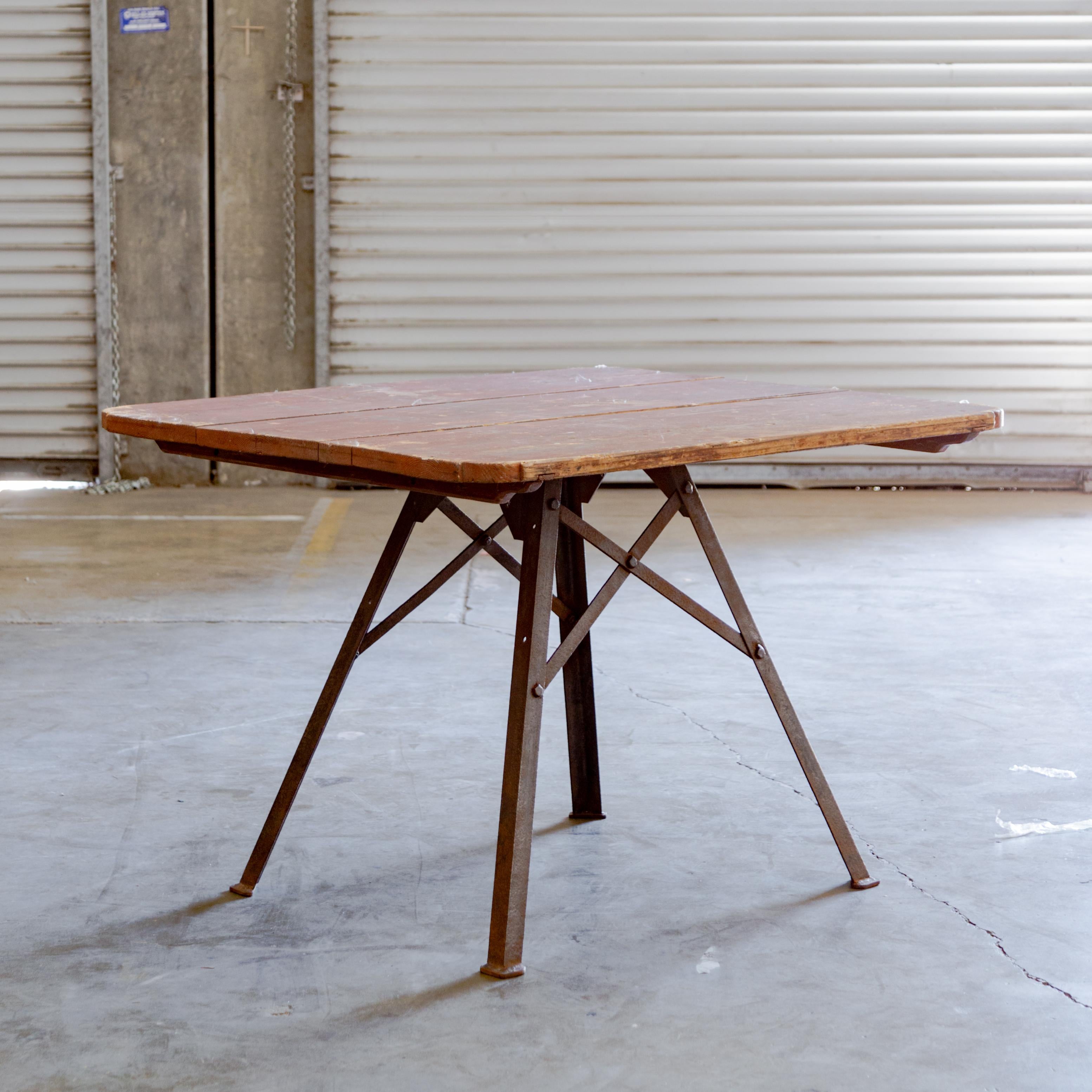 Painted plank wood tabletop on industrial metal crossbar base.
