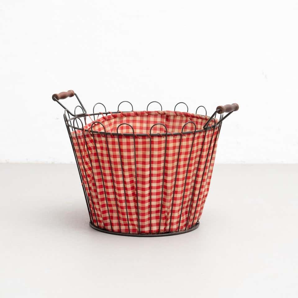 Metal basket made by welded wire completed by a solid ring. With wood handles.
Covered internally with a checkered fabric.
Unknown manufacturer, France,
Circa 1970

Materials:
Metal
Wood
Fabric
In original condition, with minor wear