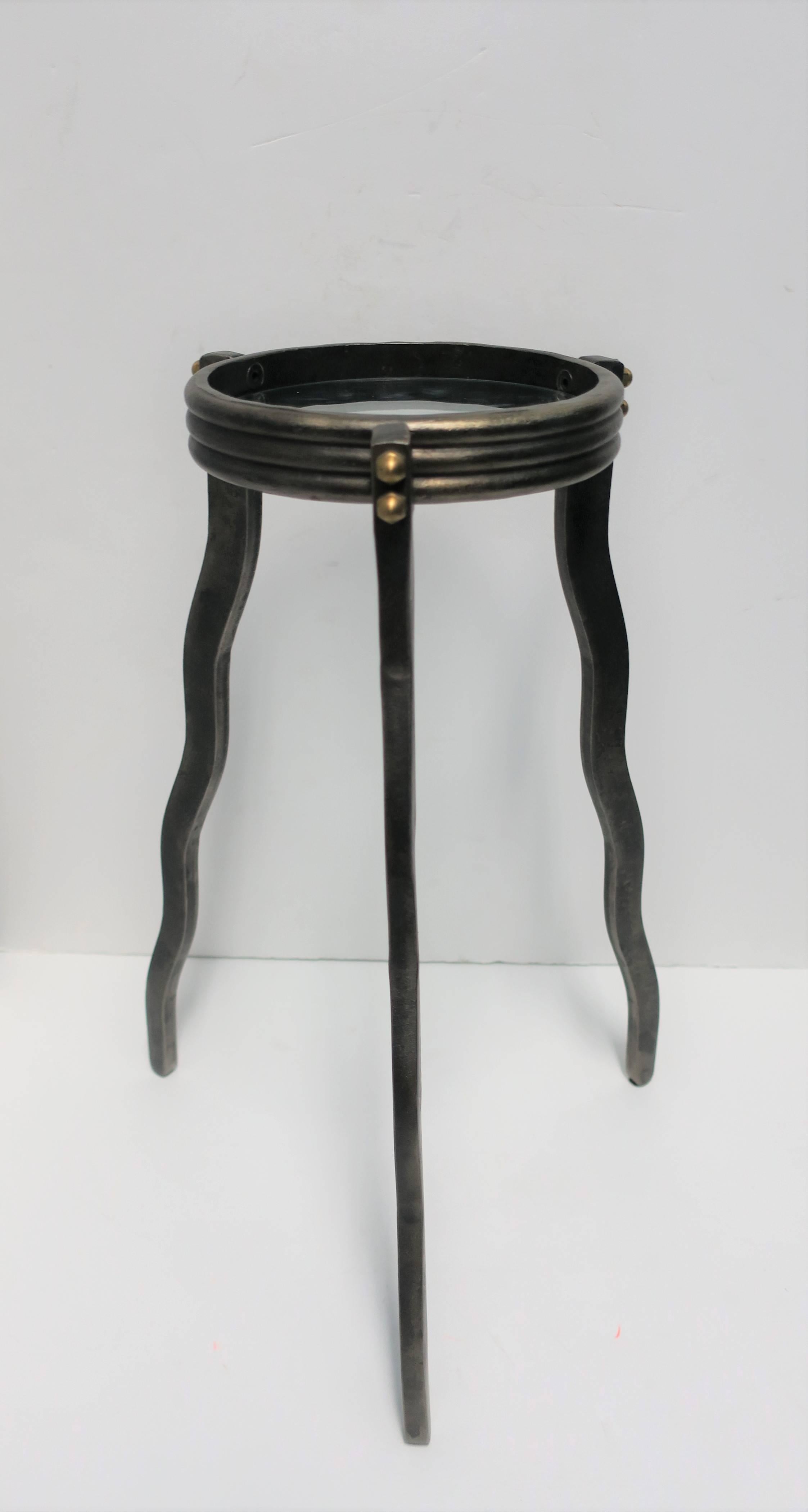 A substantial dark metal small tri pod side or drinks table with brass bolt detail, glass top, and 'wavy' legs in an Art Deco style.

Table measures: 7.50 in. diameter x 19.25 in. H

Table available here online. By request, table can be made