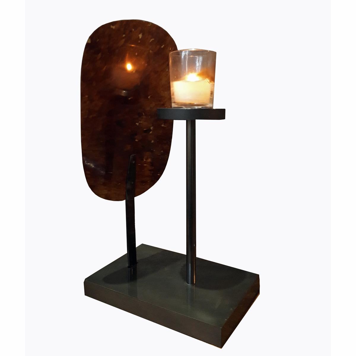 A unique votive candleholder with a black metal base and a front screen in thin tortoiseshell. The unique color of the shell screen gives the candlelight a warm, beautiful shade.
  