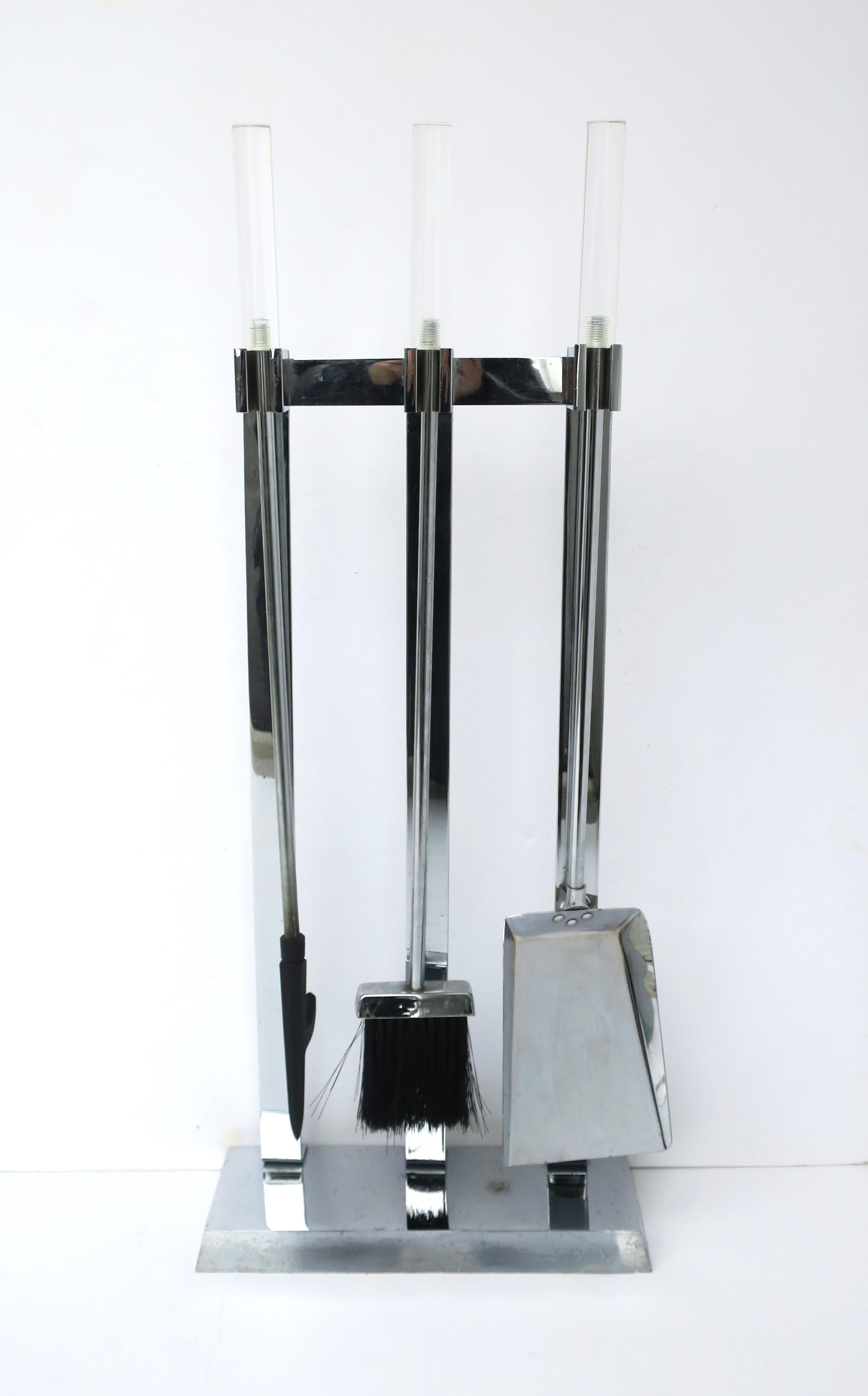 A metal chrome and Lucite fireplace tool set, in the Modern style, attributed to designer Alessandro Albrizzi, circa late-20th century. Set consists of a stand, poker, brush, and shovel; tools have Lucite handles. Tools appear to have never been