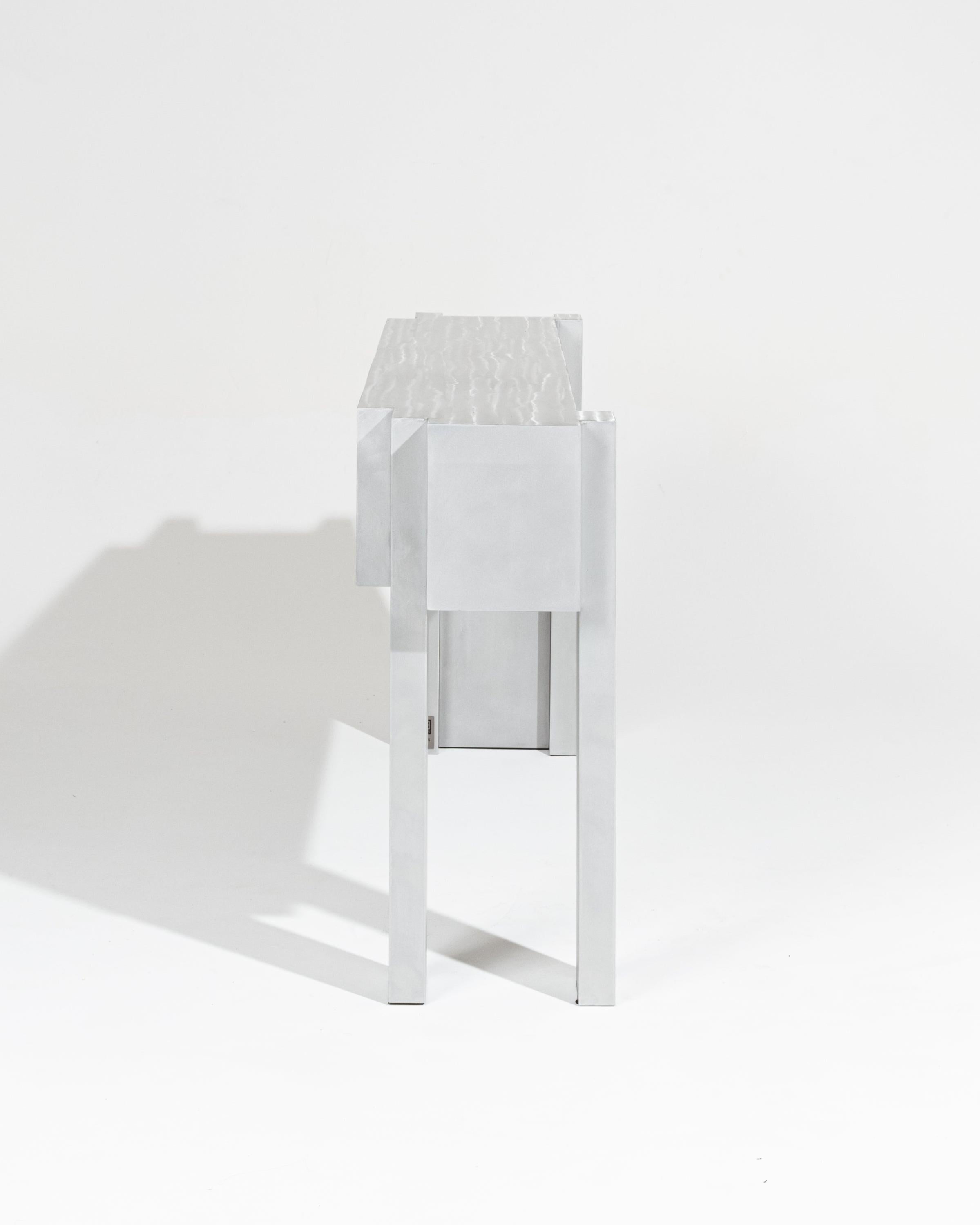Metallkonsole aus der Modulis Collection'S von Ergane Design.
Die Kollektion Modulis ist als modulares Ensemble konzipiert und passt sich an Ihren Raum an. Couchtische, Beistelltische und Bänke greifen ineinander, ergänzen sich und lassen sich frei