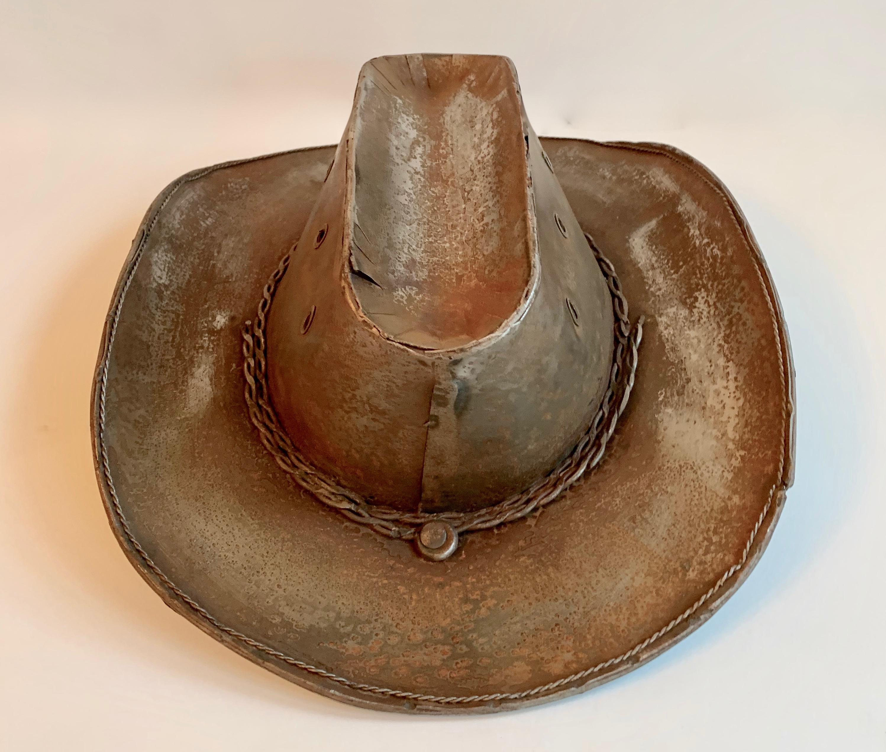 A handsome cowboy hat most likely used for display, now making a great decorative piece. Welded of metal / tin and styled with the details of any cowboy hat - air holes, rope, and the perfect bill.
