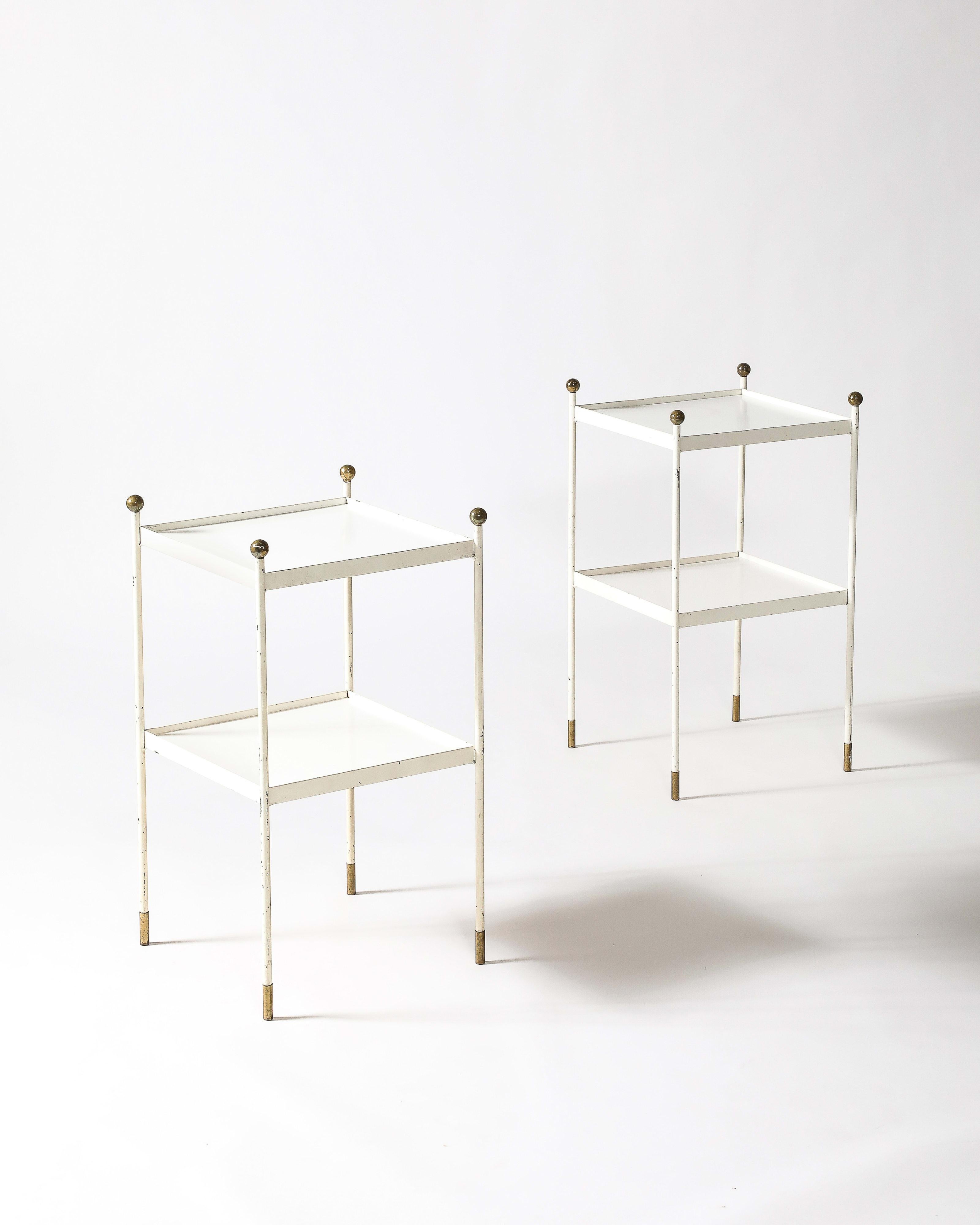 Lacquered metal end tables with brass accents at the corners, and caps on the feet. The design is reminiscent of Royere.
The tables are patinated throughout, and there is a ring mark on the very top of one of them. We like the look of the patina,